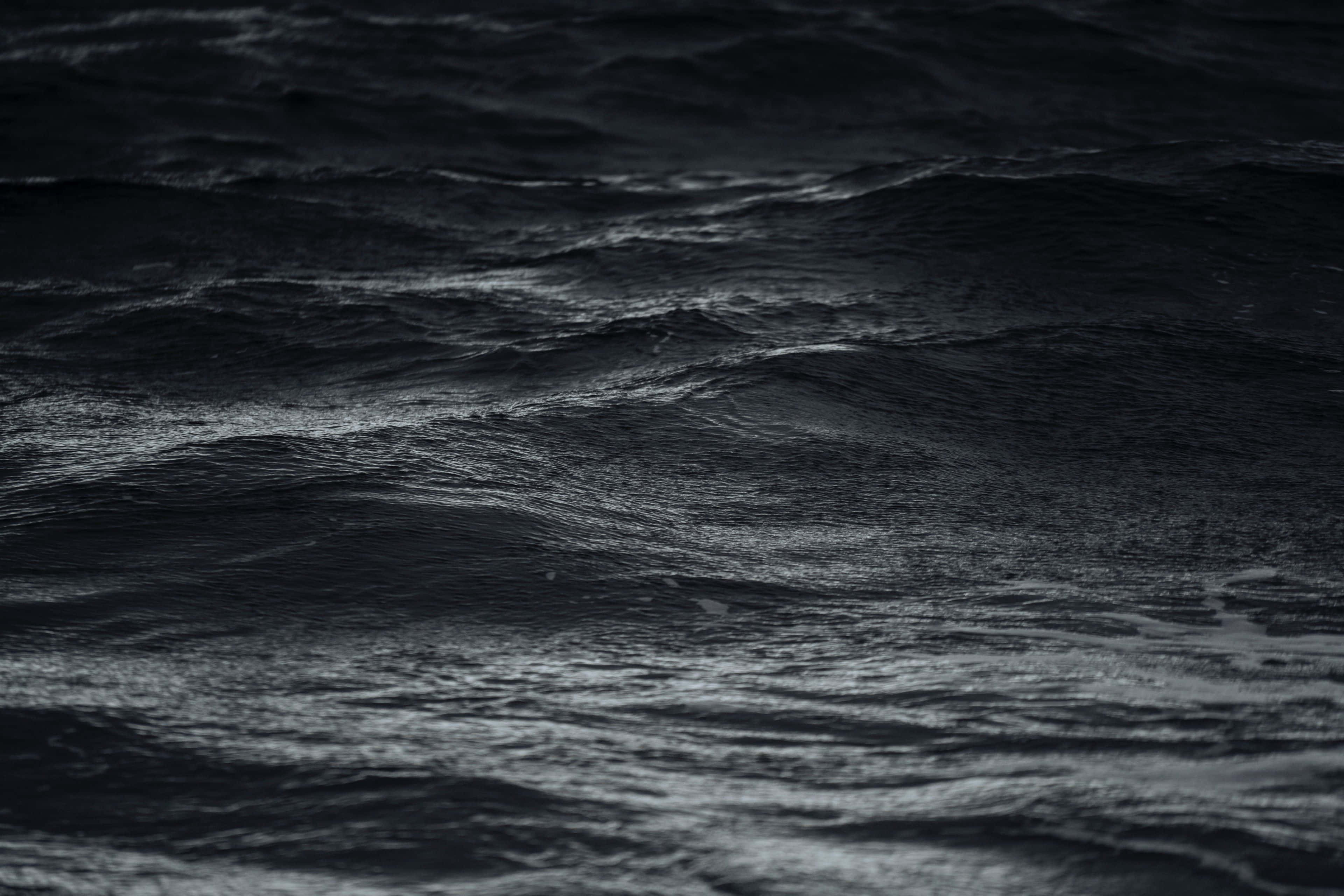 Black Sea 桌布 壁紙 — 黑暗翻騰的海浪在昏暗光線下泛起漣漪，帶有紋理泡沫和深邃陰影。