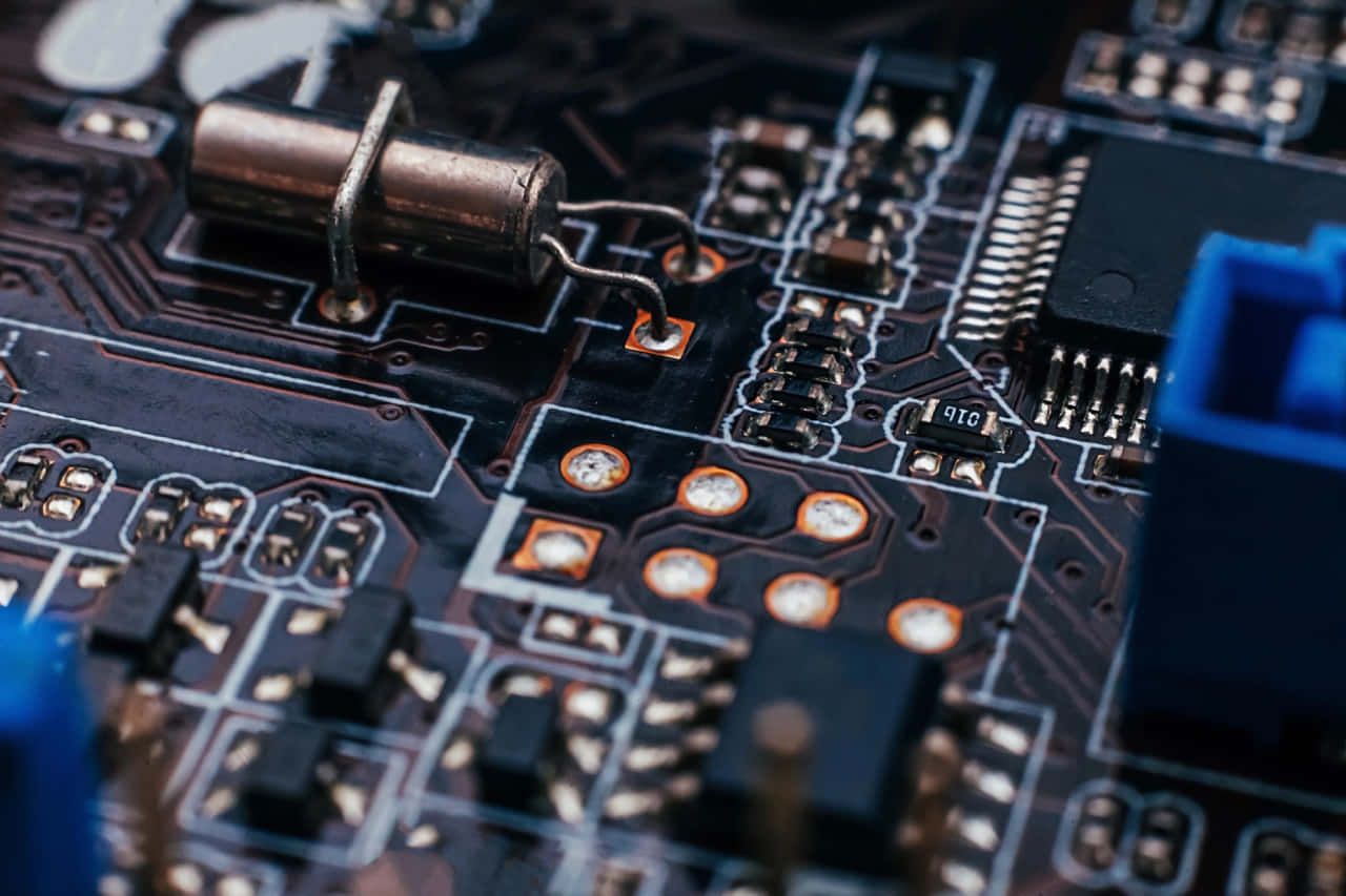 Electronic Components 桌布 壁紙 — 黑暗電路板的特寫微距鏡頭，帶有複雜的銀色路徑和發光的橙色焊點。