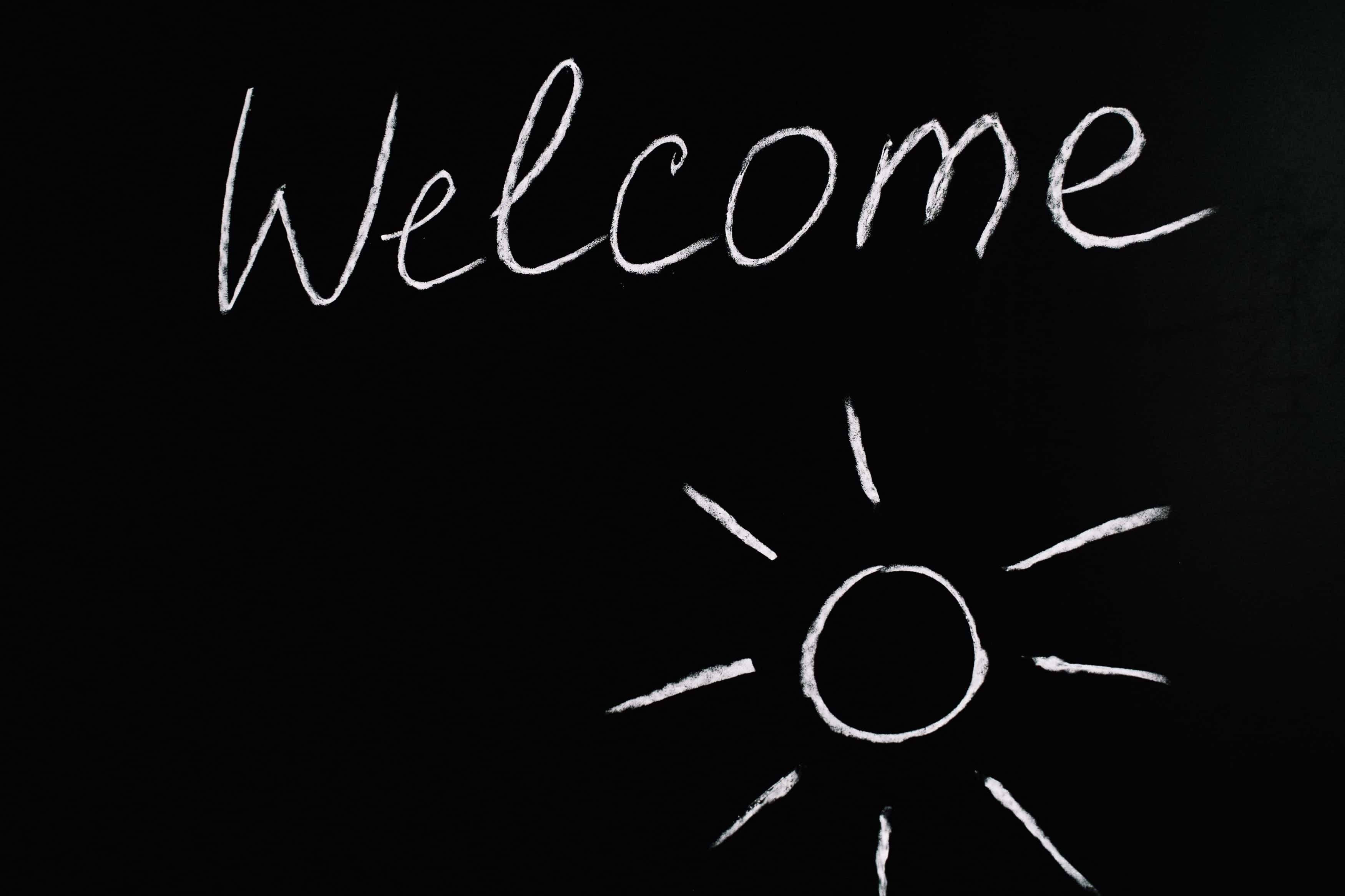 Welcome 桌布 壁紙 — 黑板上白色粉筆寫著歡迎，下方有一個手繪太陽。