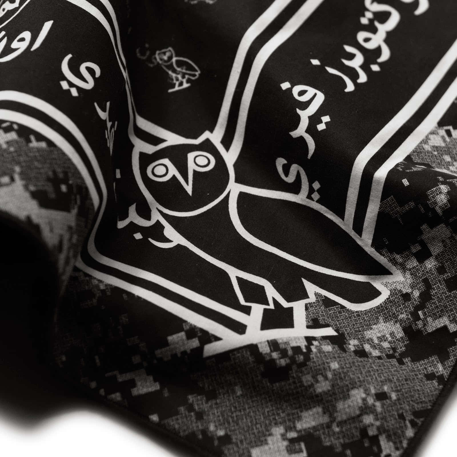Drake Ovo Owl iPhone 桌布 壁紙 — 黑白圍巾的特寫，帶有阿拉伯文字和數位迷彩圖案的風格化貓頭鷹標誌。