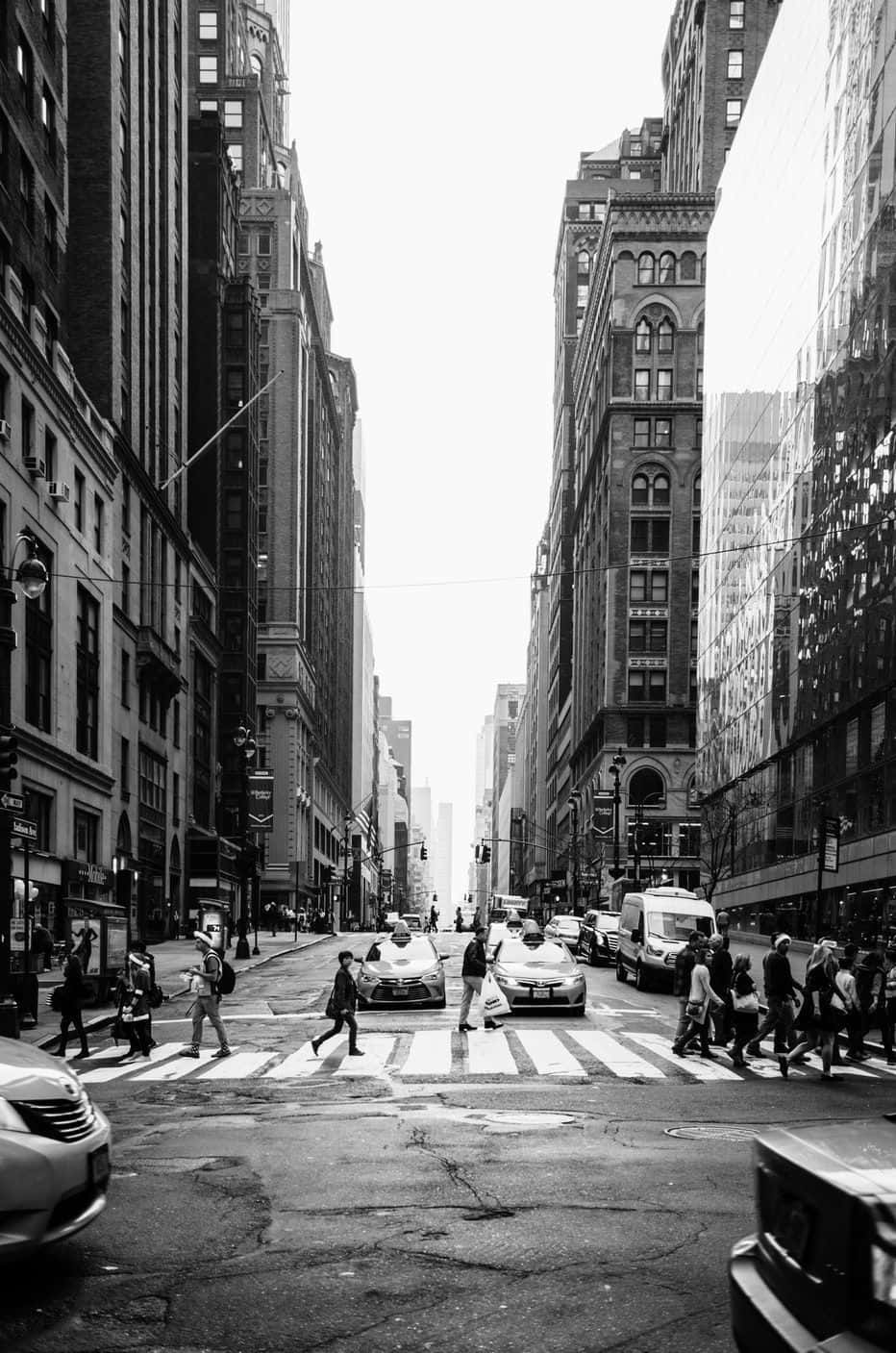 Black And White Street 桌布 壁紙 — 黑白城市街景，行人穿過高聳歷史建築之間的繁忙十字路口。