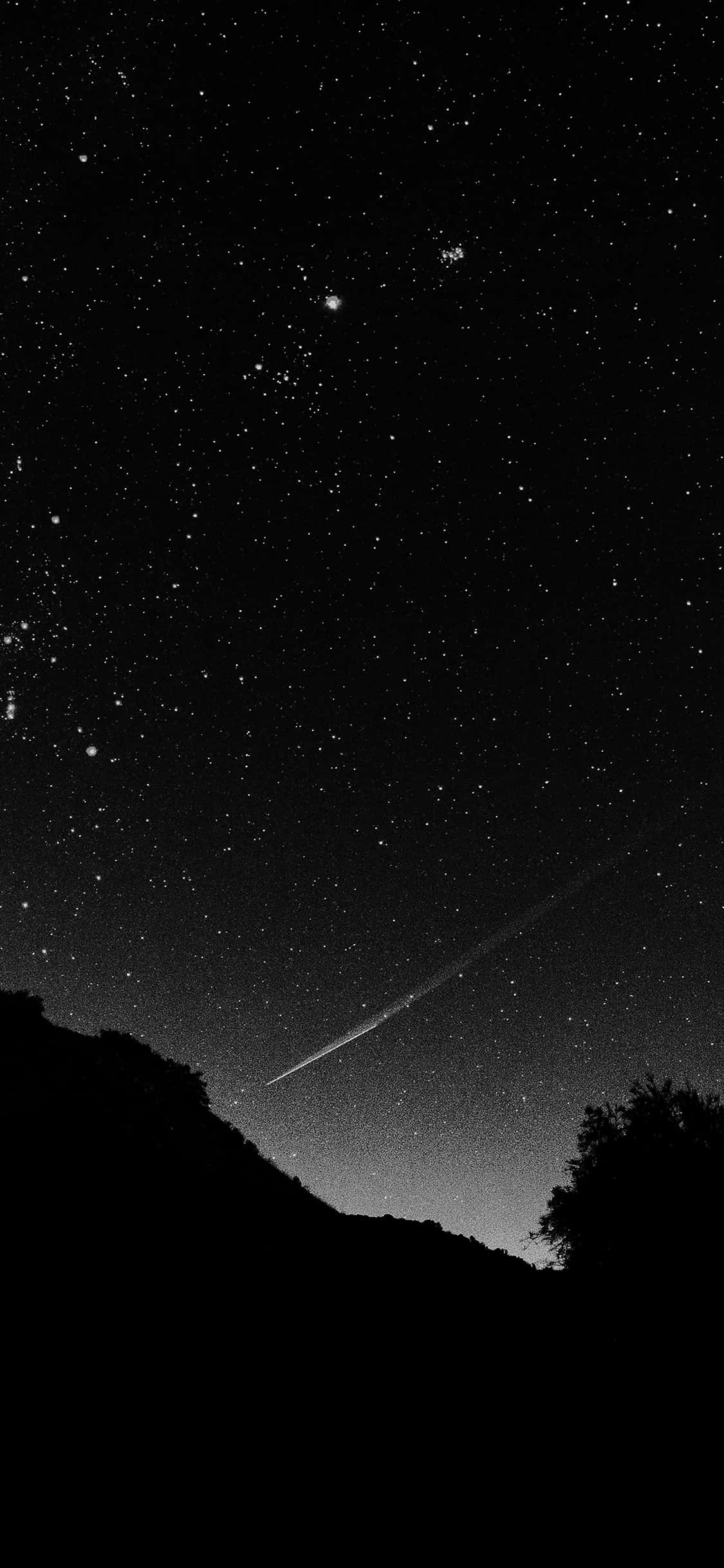 Black Space 桌布 壁紙 — 黑白夜空，滿天繁星，一顆明亮的流星劃過黑暗剪影的山丘和樹木。
