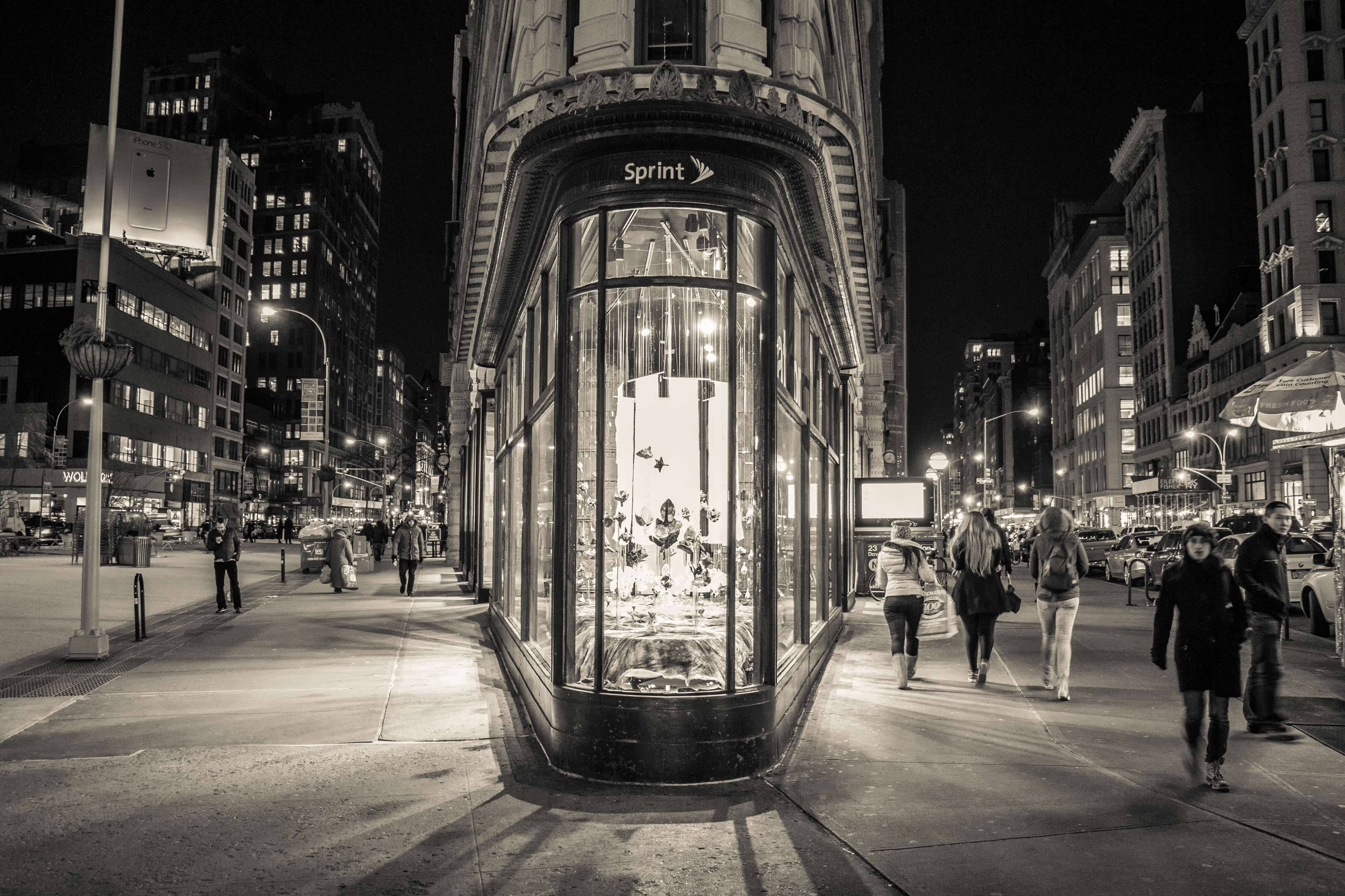 New York 桌布 壁紙 — 黑白夜間城市街道場景，行人經過燈火通明的Sprint商店角落。