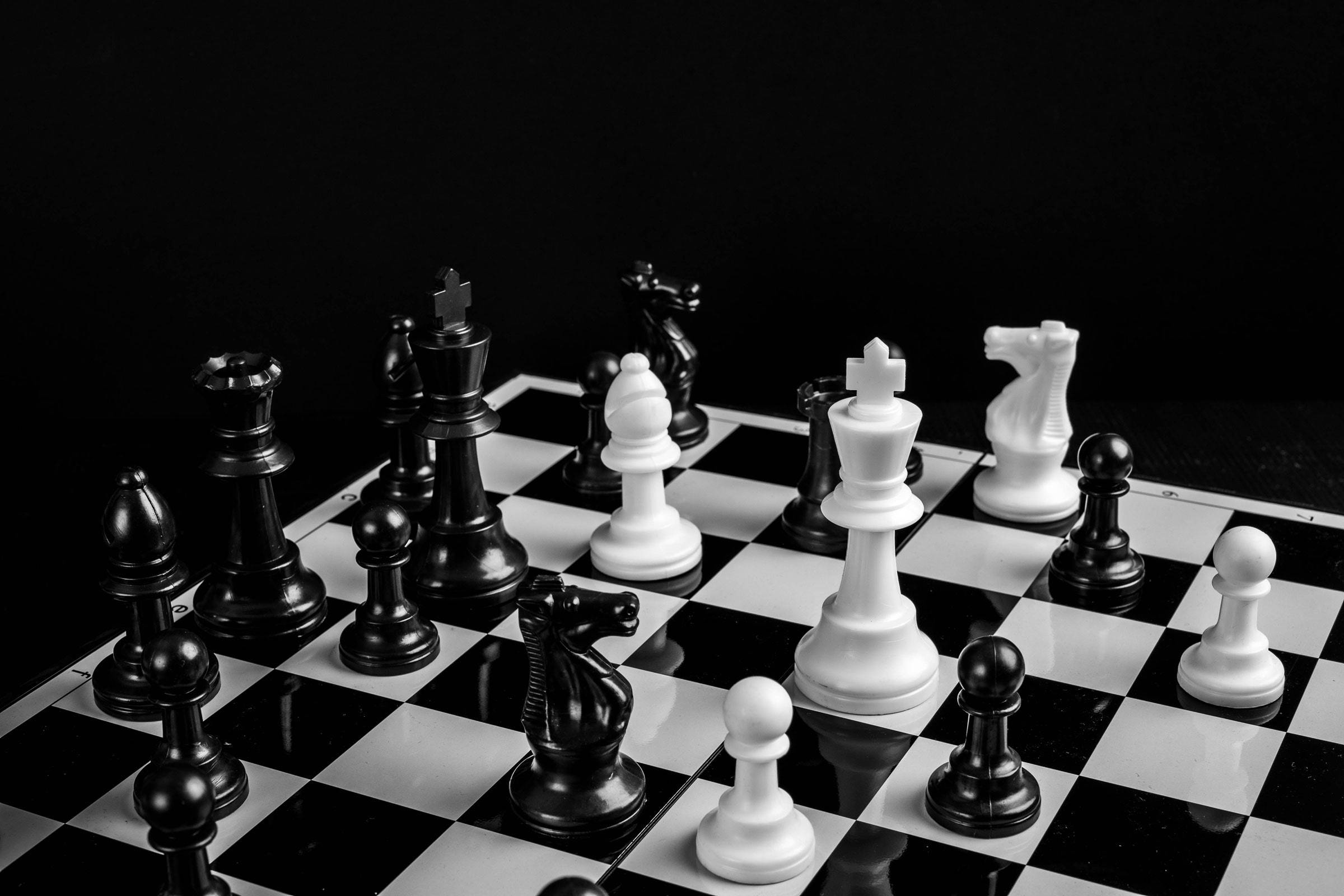 西洋棋 桌布 壁紙 — 黑白棋子在棋盤上蓄勢待發，背景為 stark 的深色。