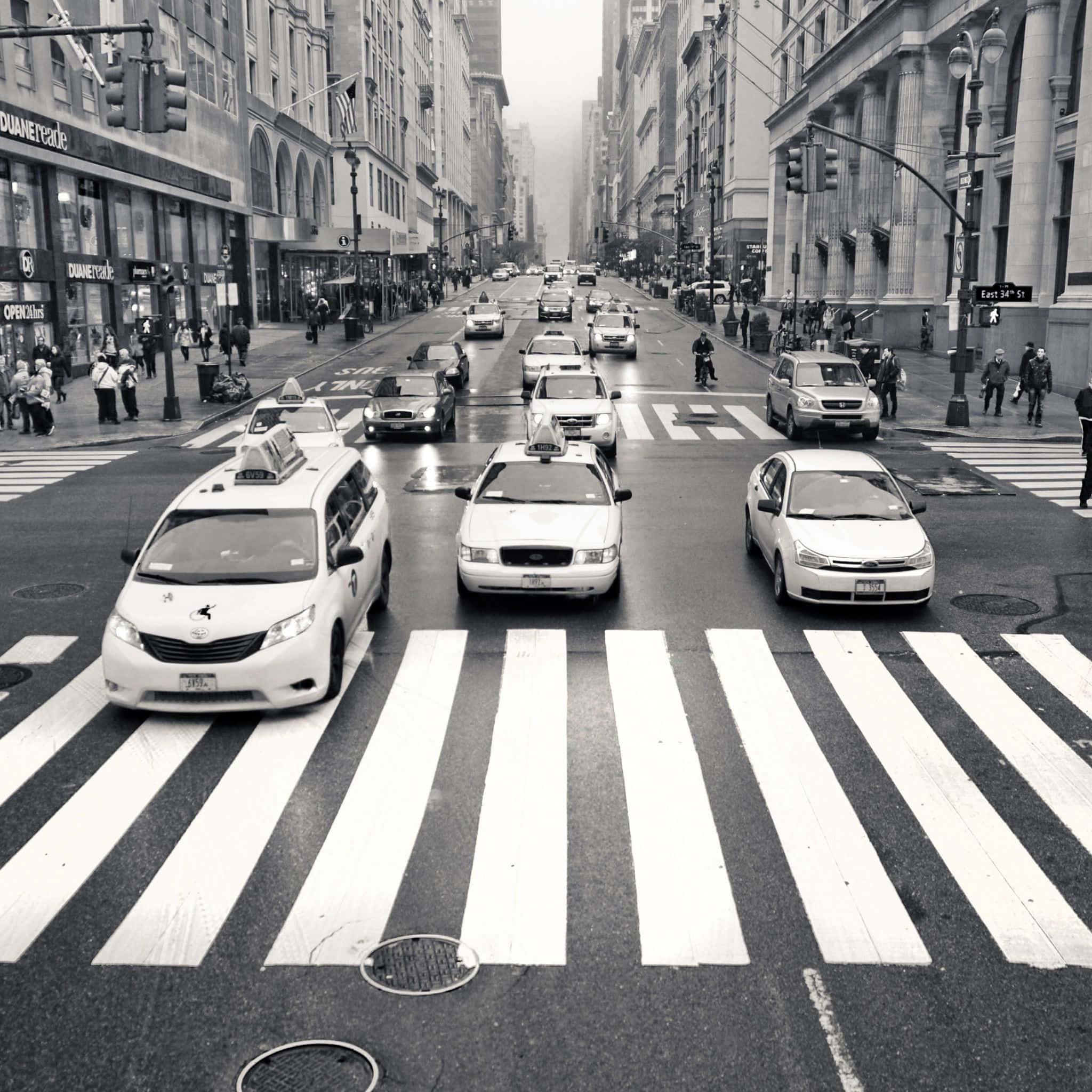 Black And White Street 桌布 壁紙 — 黑白照片，繁忙的城市街道上，計程車和行人在陰天穿越濕漉漉的行人穿越道。