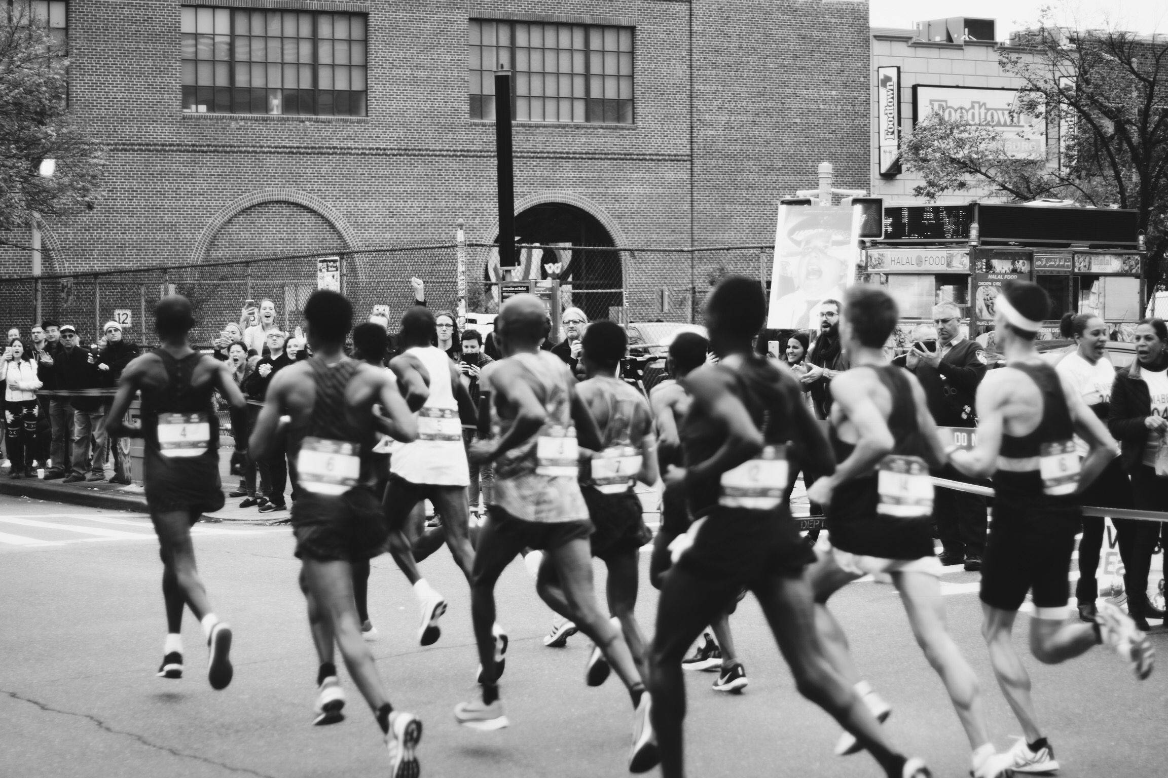 Marathon 桌布 壁紙 — 黑白照片，跑者在城市街道上衝刺，觀眾在圍欄後歡呼。