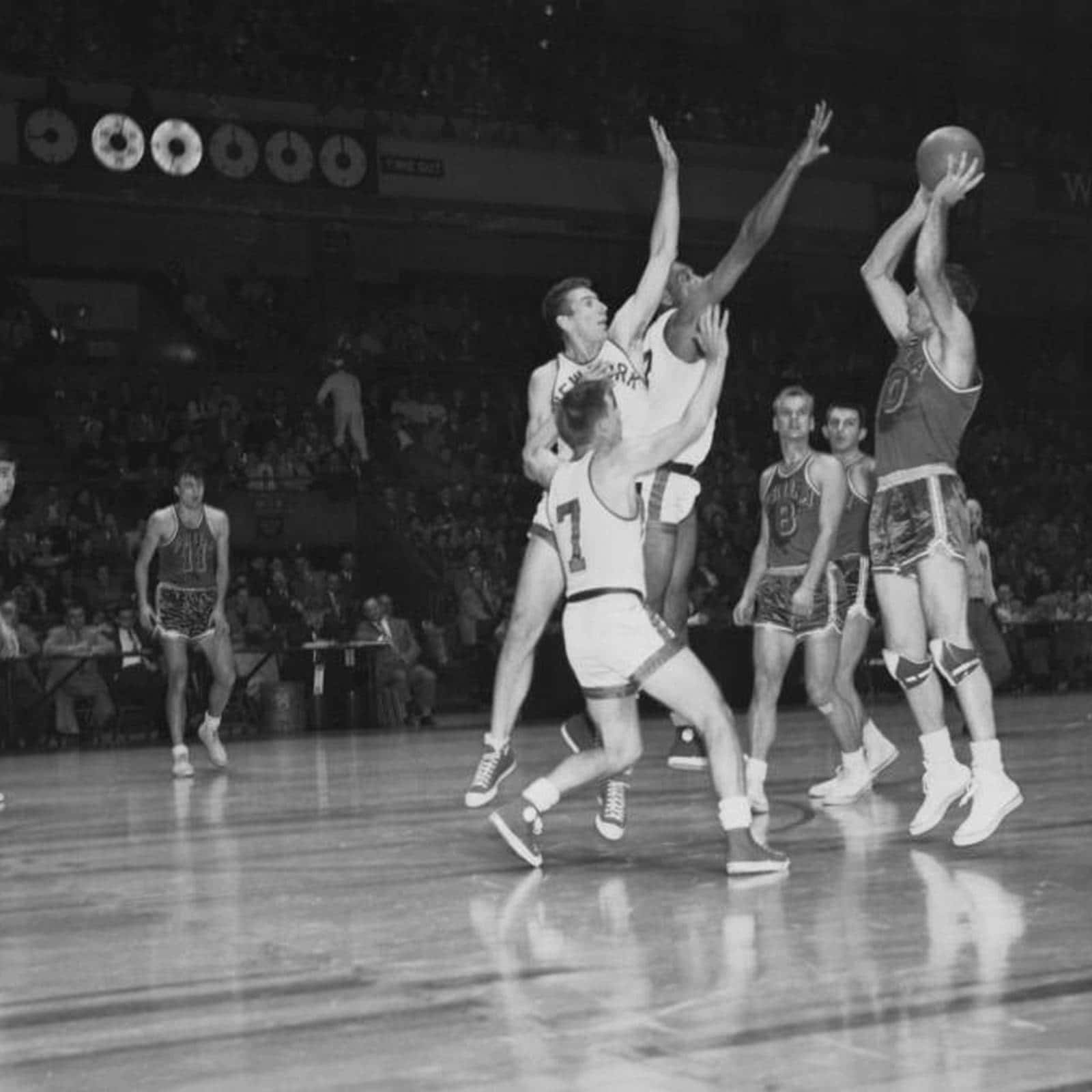 復古籃球運動員在場館燈光下於比賽中騰空。 — NBA 壁紙