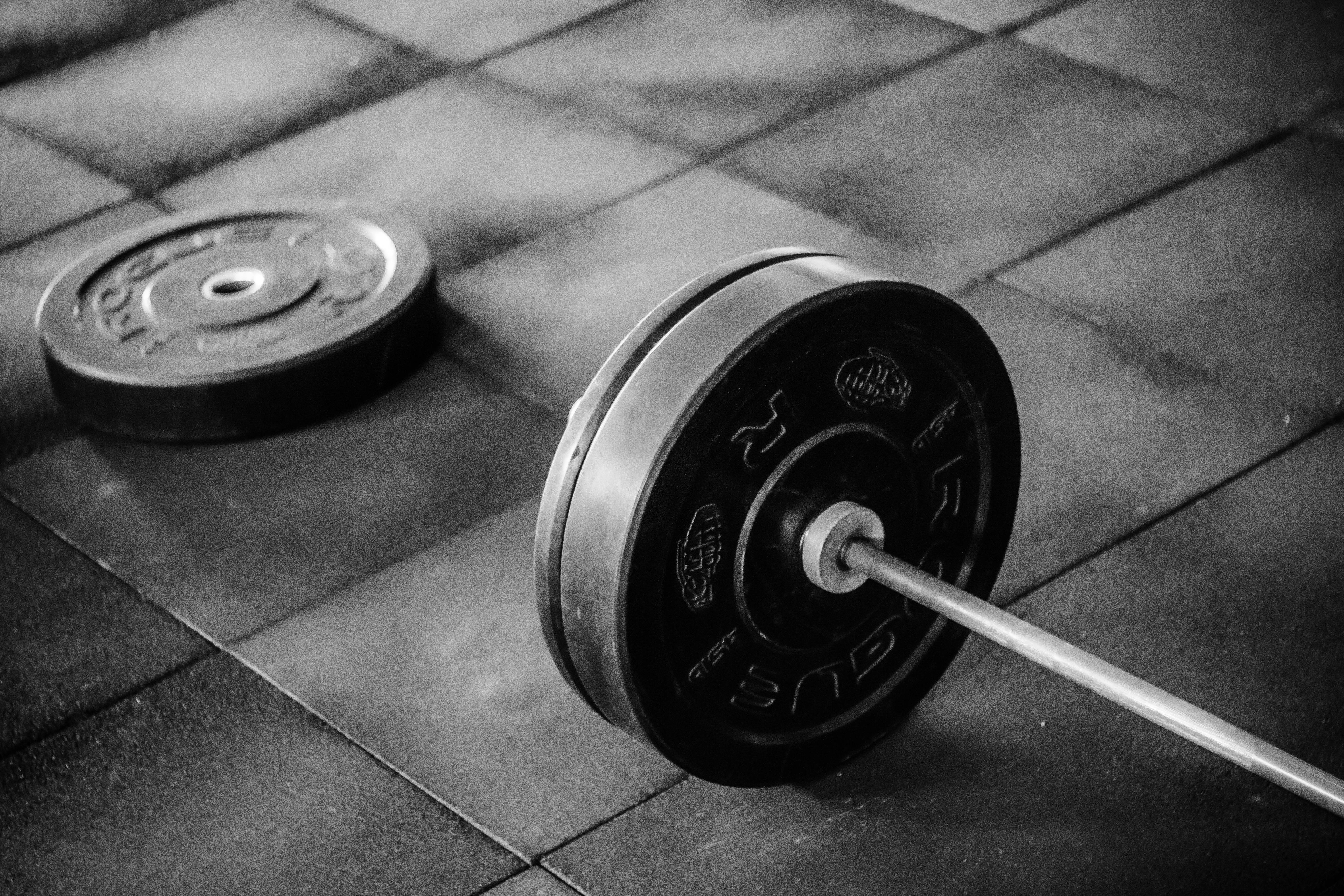 Barbell 桌布 壁紙 — 黑白特寫，槓鈴配重片放在健身房地磚上。