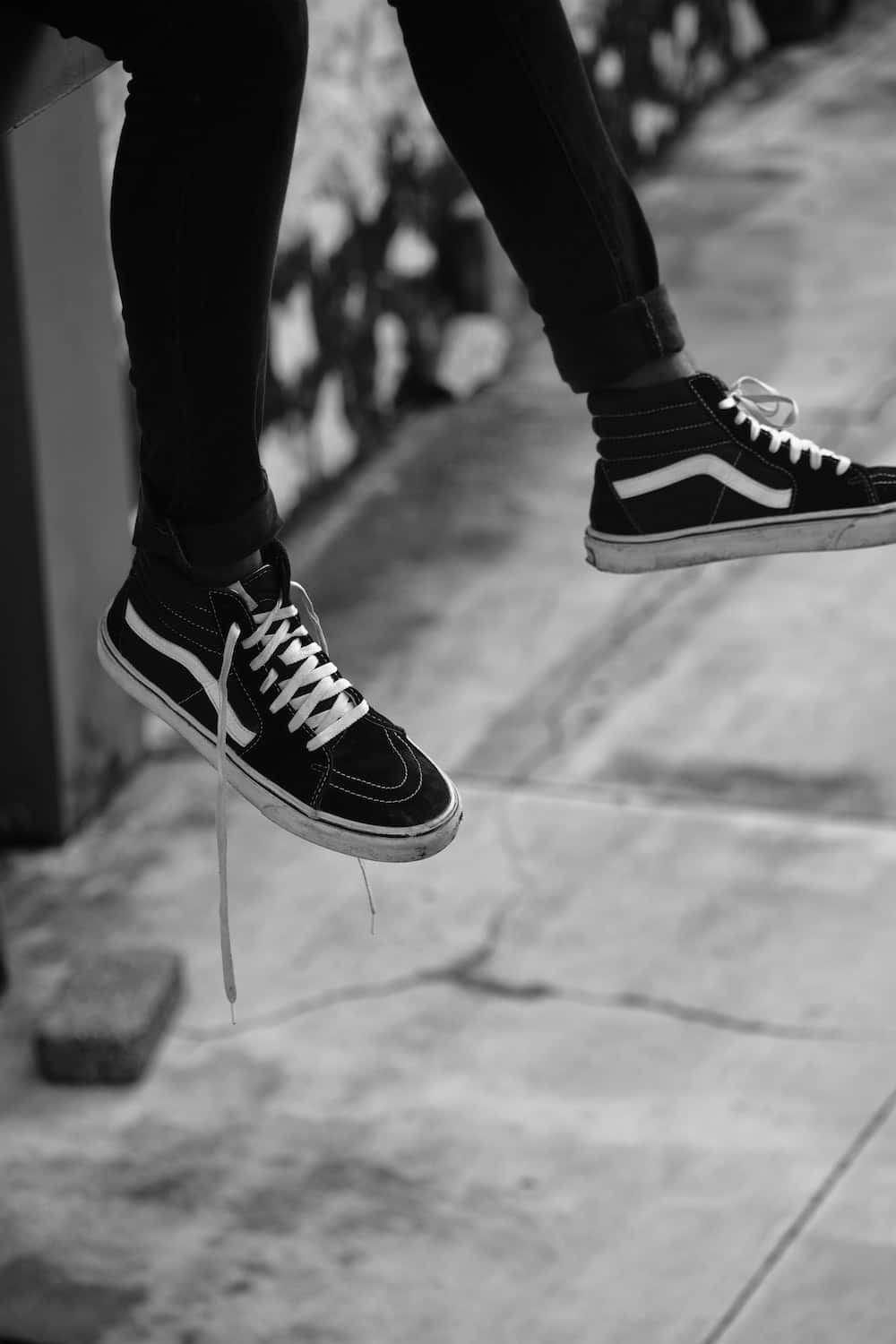 Vans 桌布 壁紙 — 黑白特寫，腳穿經典Vans運動鞋，懸空於石鋪路面上方。