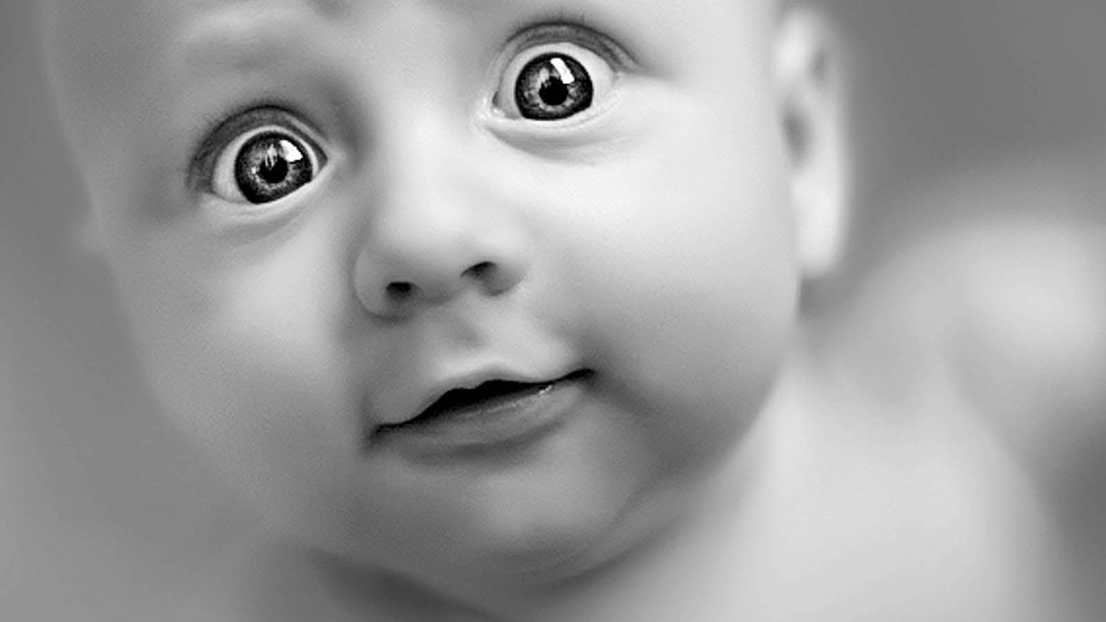 Funny Baby 桌布 壁紙 — 黑白特寫嬰兒的臉部，眼睛睜大受驚，嘴巴微張。