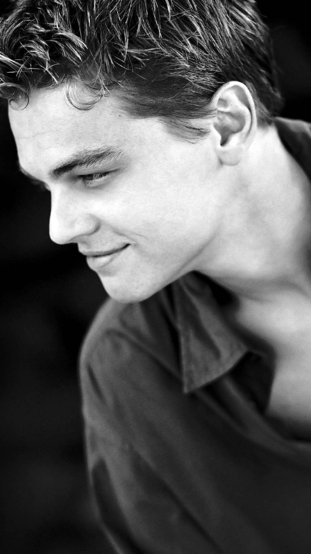 Dicaprio 桌布 壁紙 — 黑白特寫肖像，一個頭髮凌亂的年輕男子微笑著低頭。
