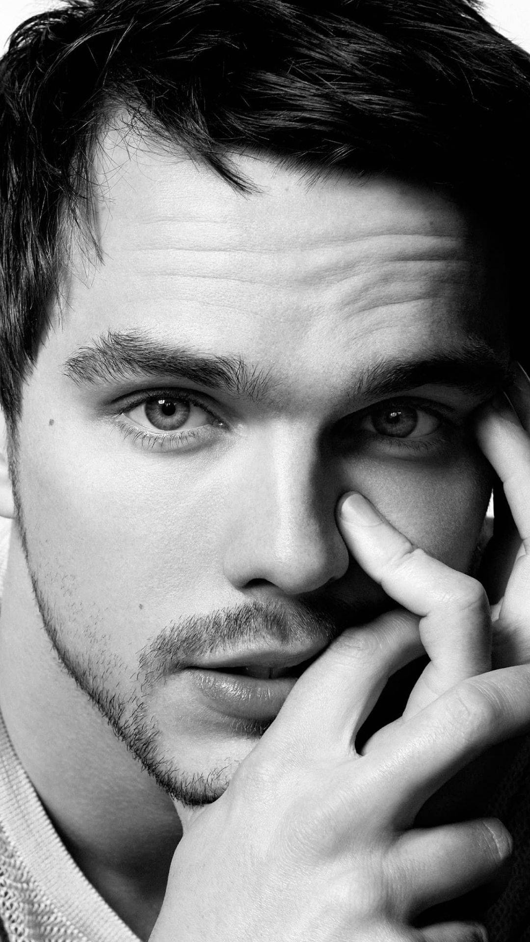 Nicholas Hoult 桌布 壁紙 — 黑白特寫肖像，一名眼神銳利的男子，手靠近臉部。