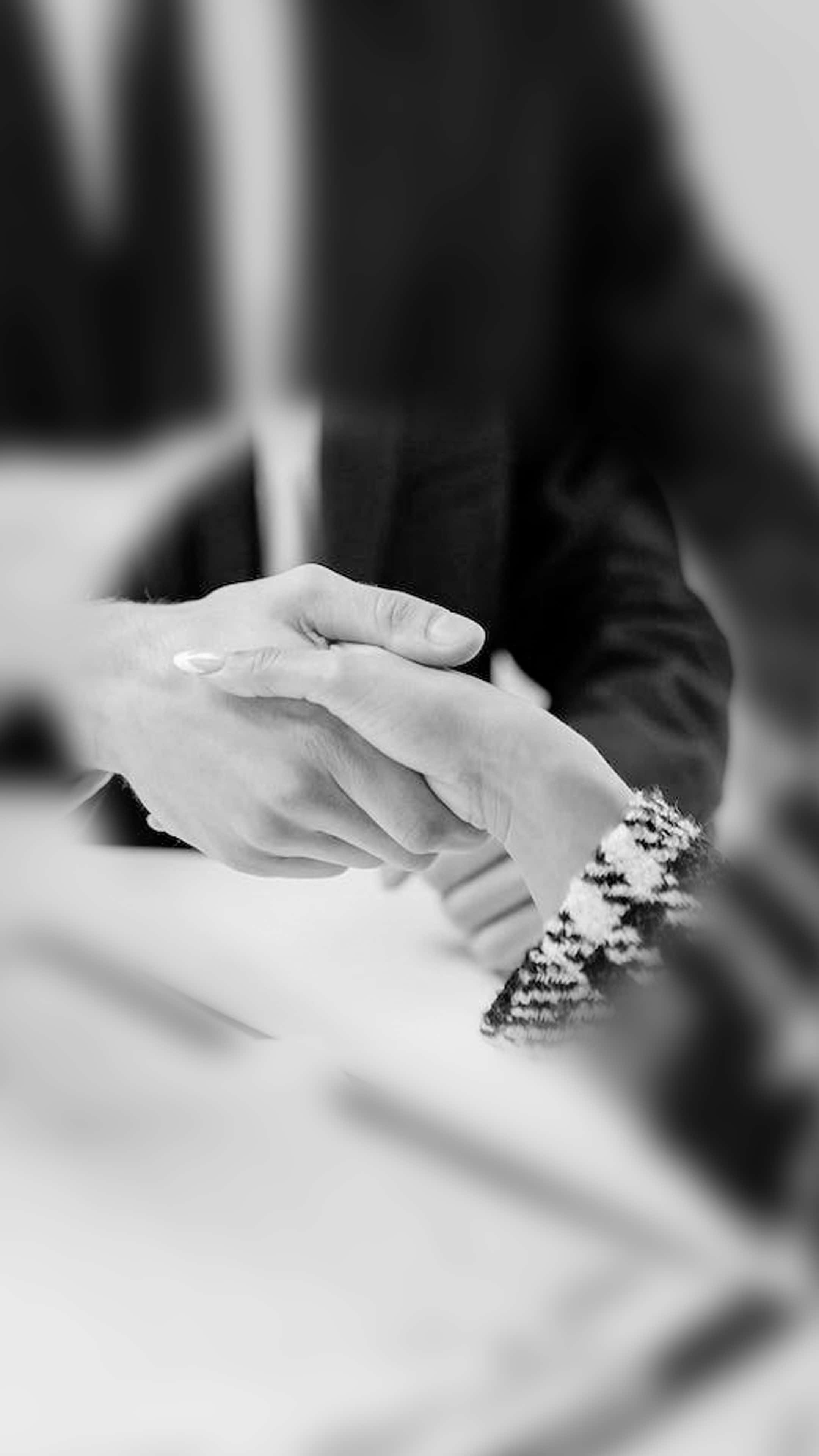 人物 桌布 壁紙 — 黑白特寫鏡頭，兩隻手緊握握手，其中一隻穿著圖案袖。