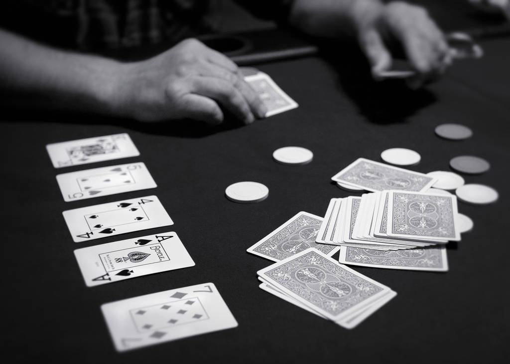 Poker Table 桌布 壁紙 — 黑白特寫鏡頭，手在深色氈桌上玩撲克牌和籌碼。