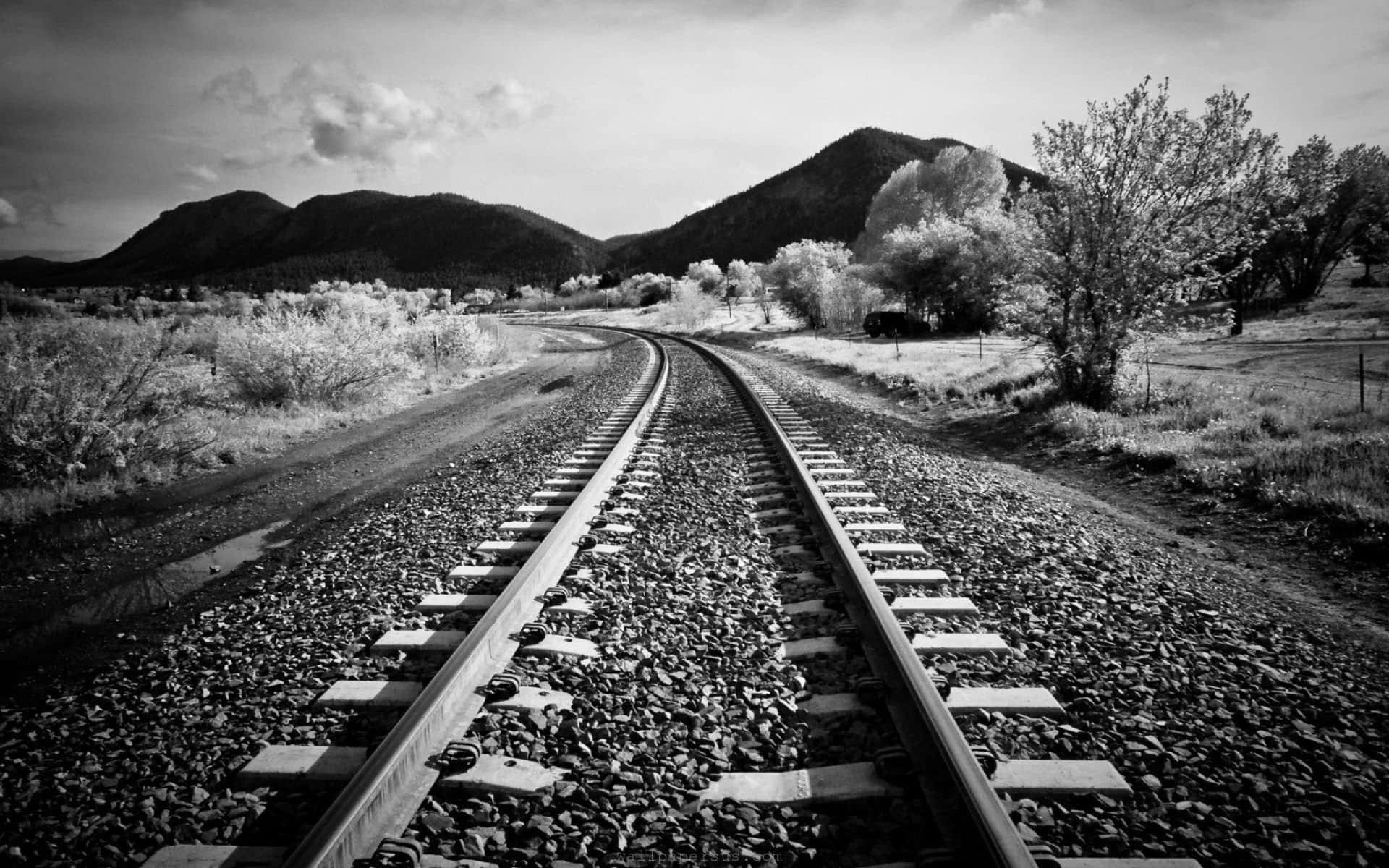 Black And White Nature 桌布 壁紙 — 黑白紅外線照片，展示鐵路軌道蜿蜒穿過沙漠景觀，朝向遠山。