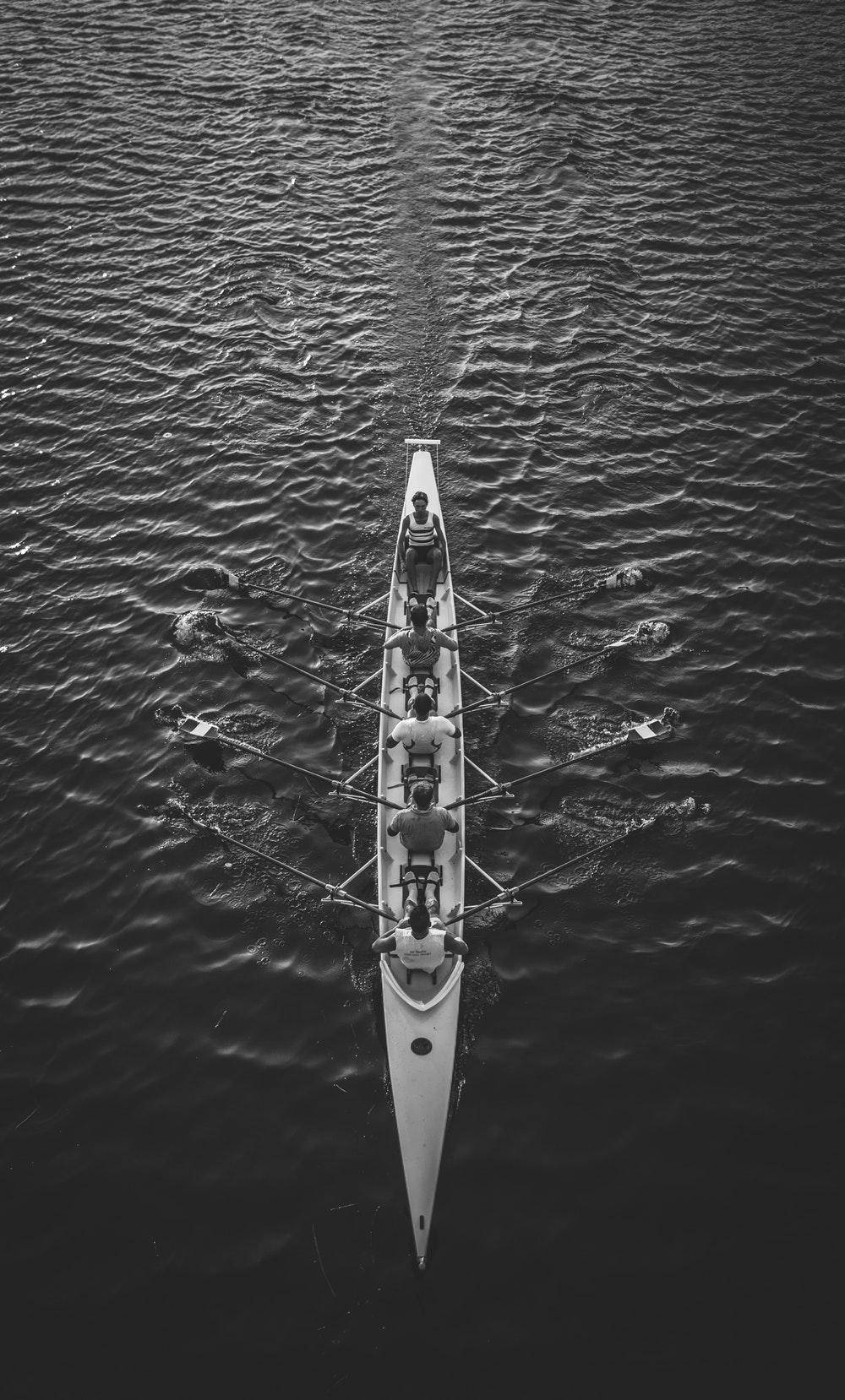 Rowing 桌布 壁紙 — 黑白航拍圖，展現划艇隊伍以同步划槳在紋理水面上滑行。