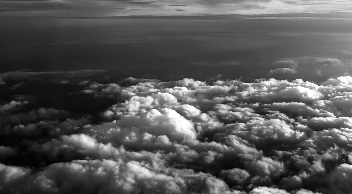 Black And White Sky 桌布 壁紙 — 黑白航空視角，翱翔於紋理豐富的雲層之上，柔和漸變延伸至遠方地平線。