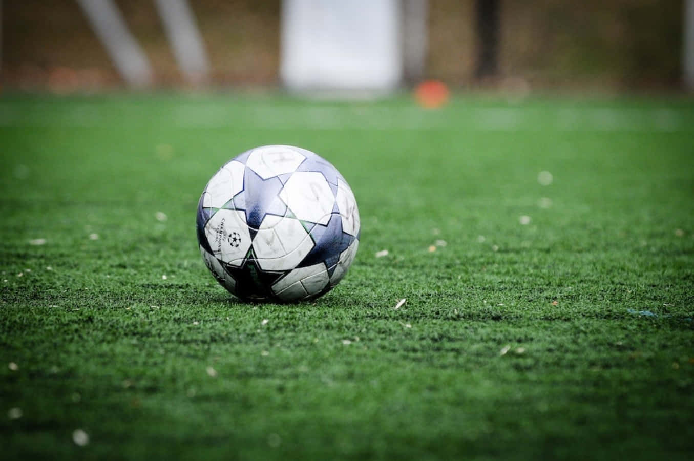 Soccer Ball 桌布 壁紙 — 黑白足球特寫，放置在鮮綠色人造草地上，背景為模糊的體育場。