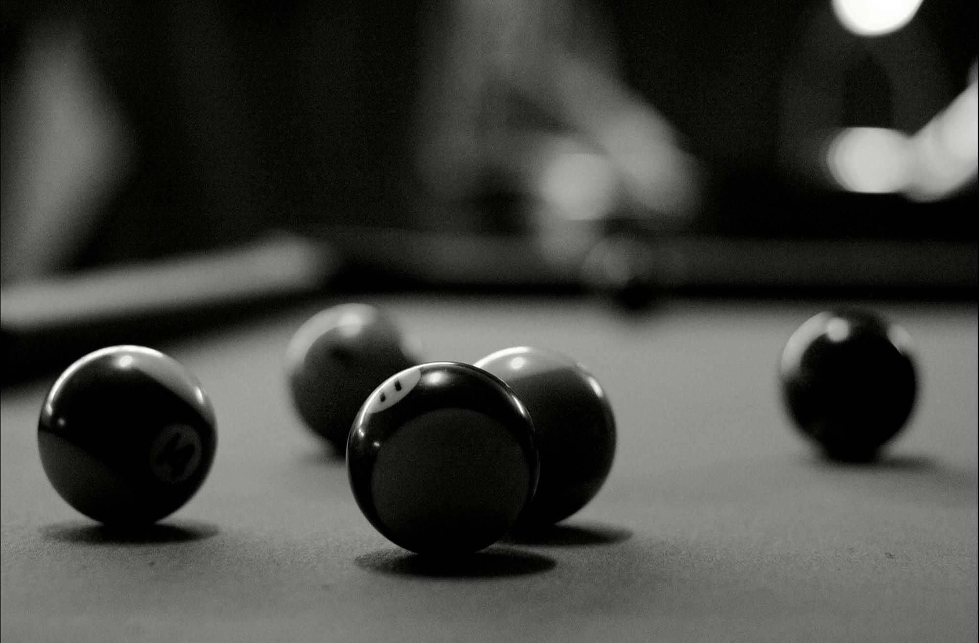Snooker 桌布 壁紙 — 黑白近距離拍攝的撞球，放在絨布桌上，背景有模糊的球桿和燈光。