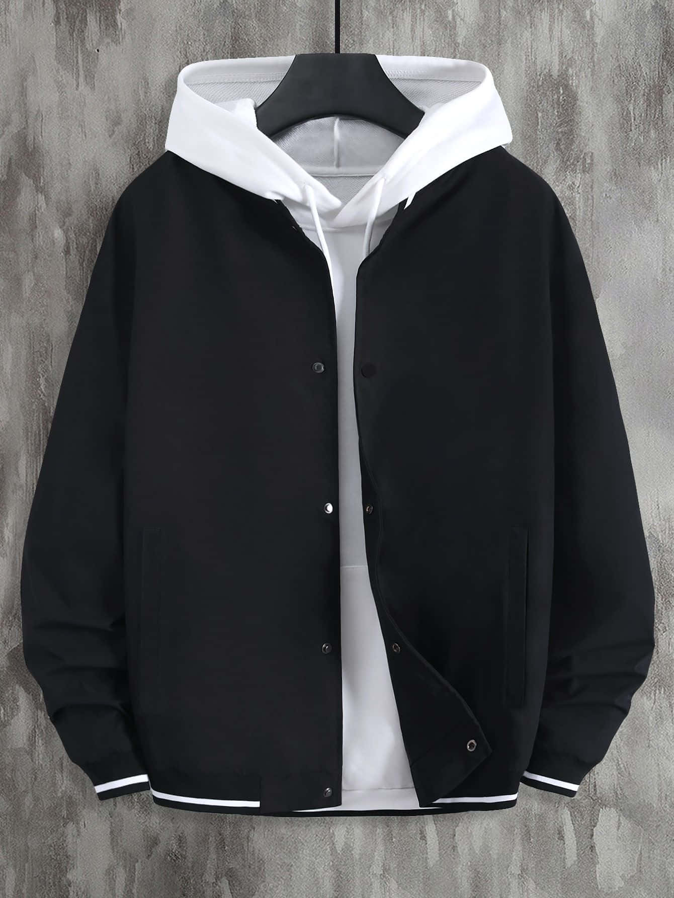 Black Clothing 桌布 壁紙 — 黑白連帽外套，前襟有鈕扣和對比色飾邊，掛在衣架上，背景是紋理灰色牆壁。