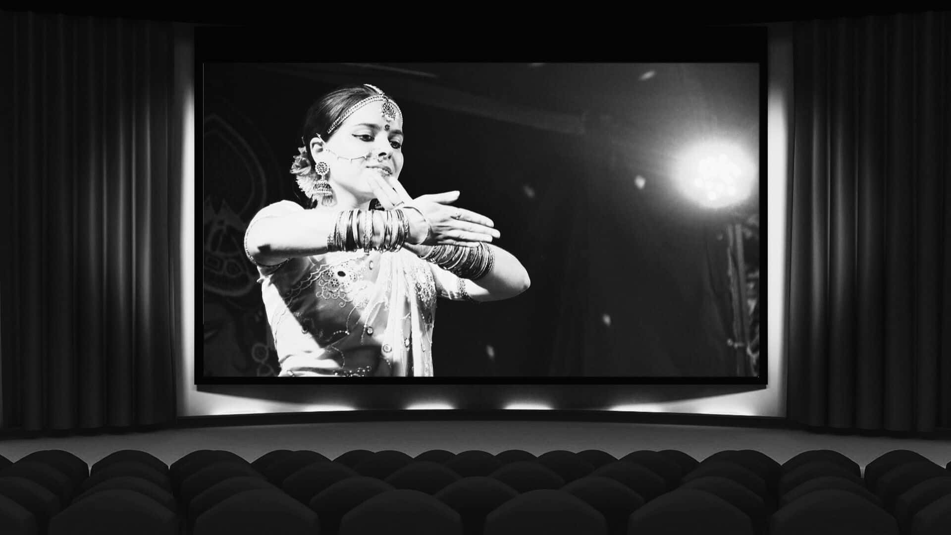 Black And White Movie 桌布 壁紙 — 黑白電影螢幕顯示一位穿著傳統服飾的優雅舞者在舞台上以戲劇性燈光表演。