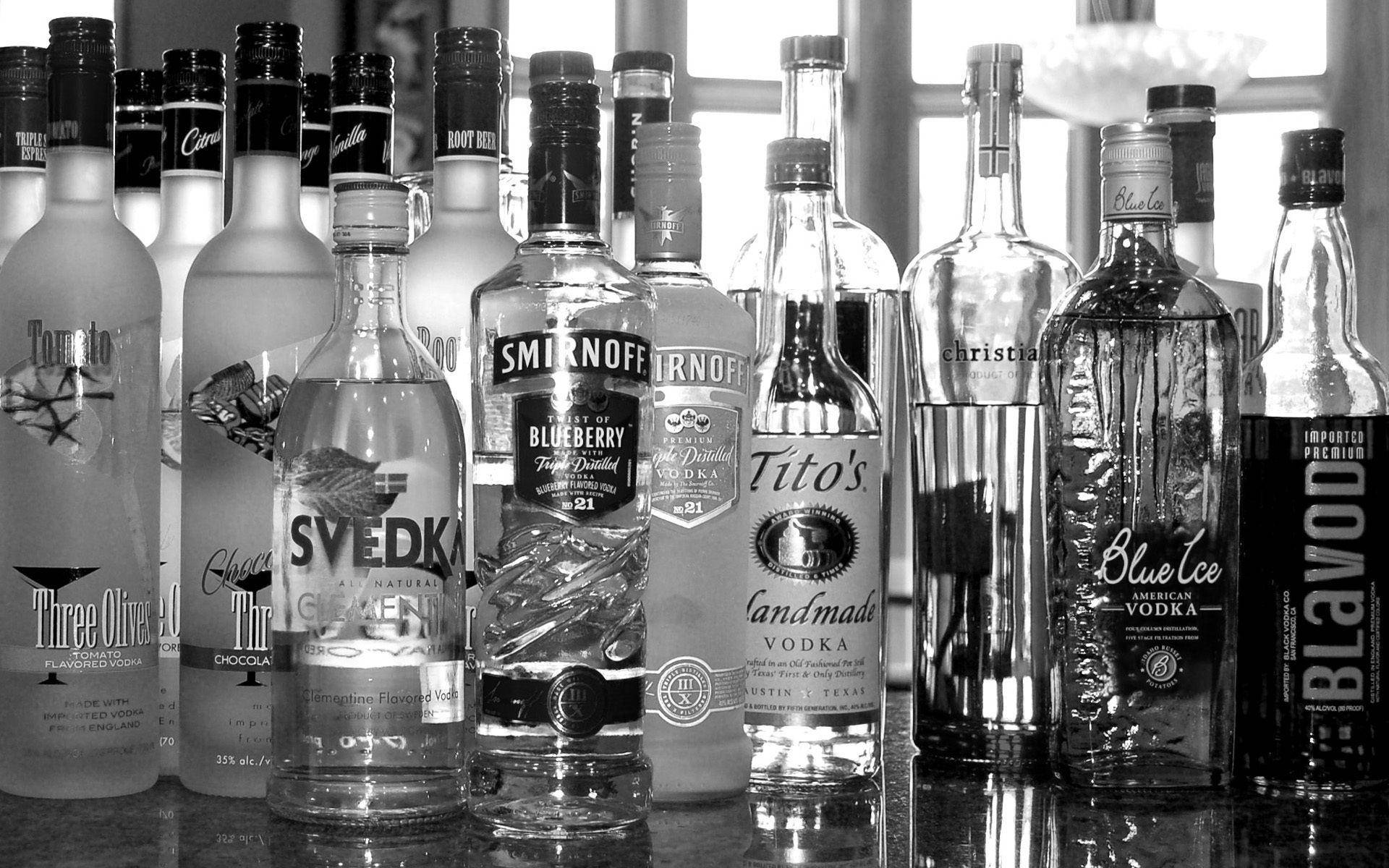alcohol 桌布 壁紙 — 黑白靜物攝影，各種伏特加酒瓶排列在反光表面上，柔和窗光照射。