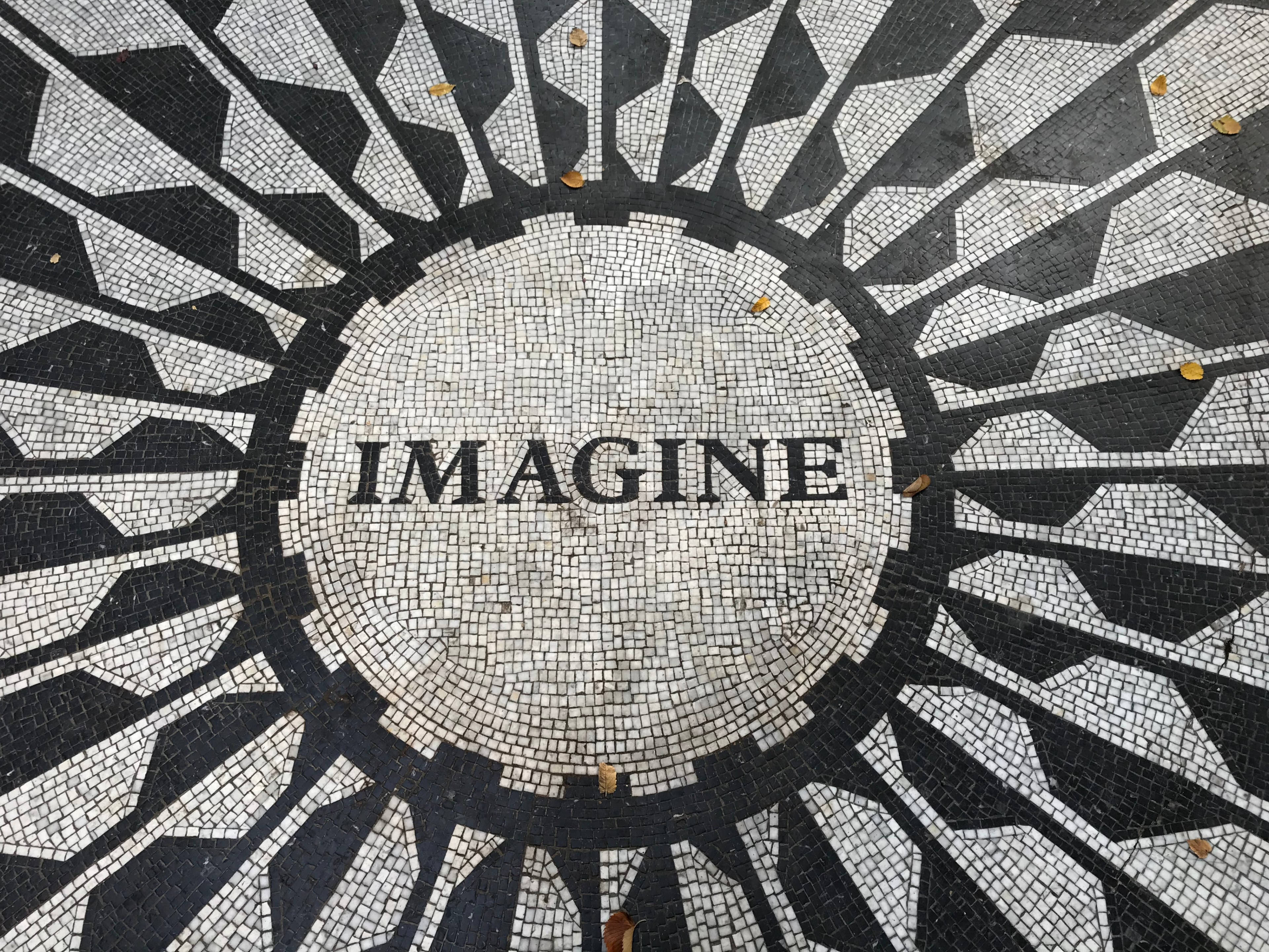 黑白 桌布 壁紙 — 黑白馬賽克地板中央有「IMAGINE」字樣，周圍環繞著幾何太陽光線圖案和散落的秋葉。