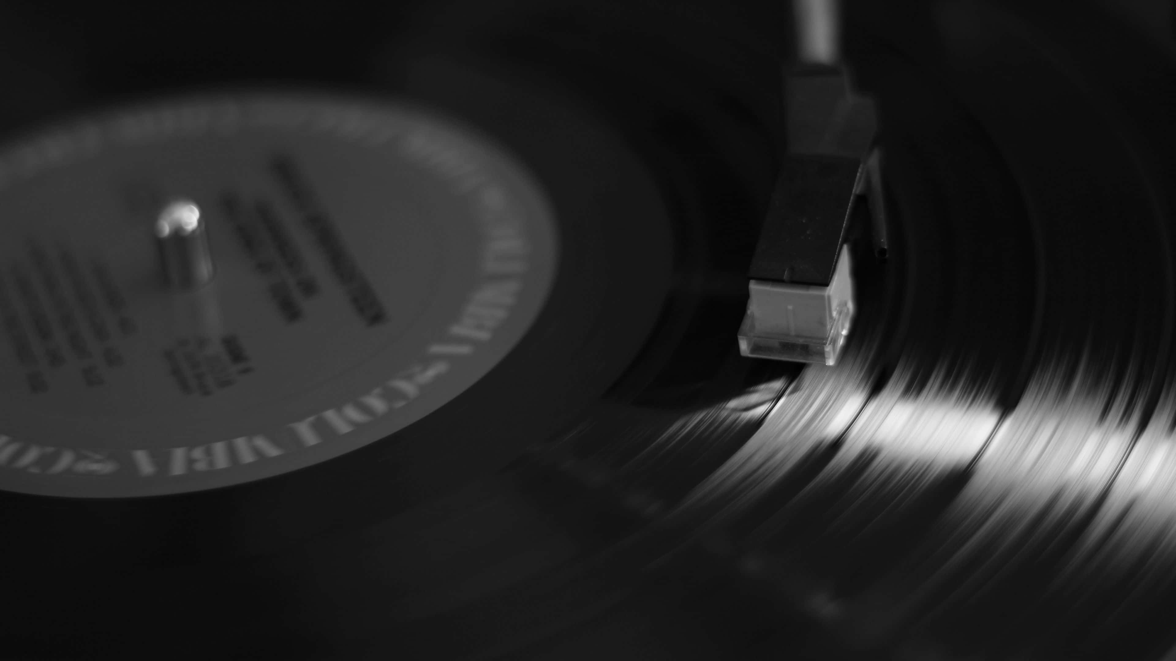 record 桌布 壁紙 — 黑膠唱片在唱盤上旋轉的單色特寫，唱針輕輕放在唱片溝槽上。
