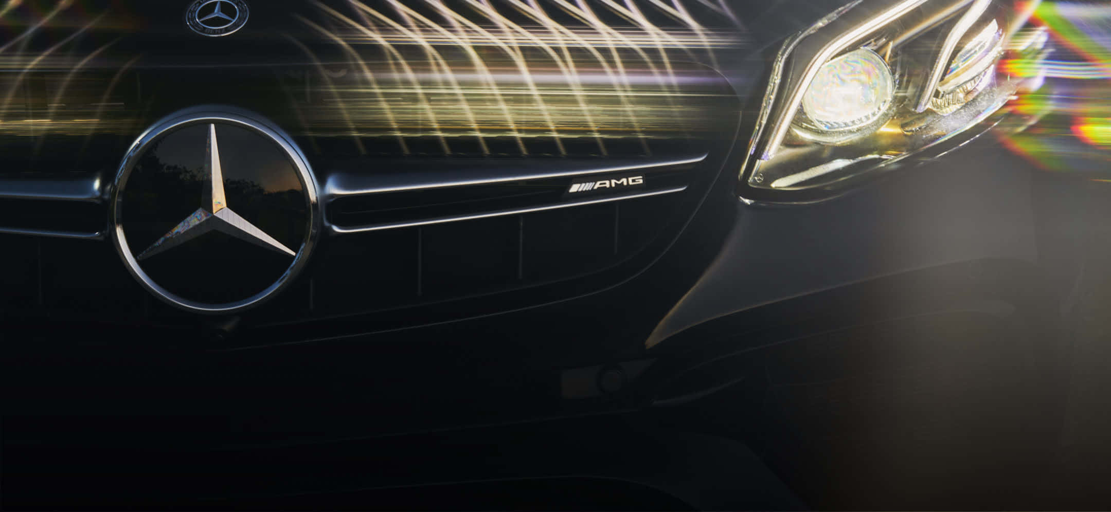 Mercedes 桌布 壁紙 — 黑色 Mercedes-AMG 水箱護罩及頭燈特寫，帶有發光光條和彩虹鏡頭光暈。
