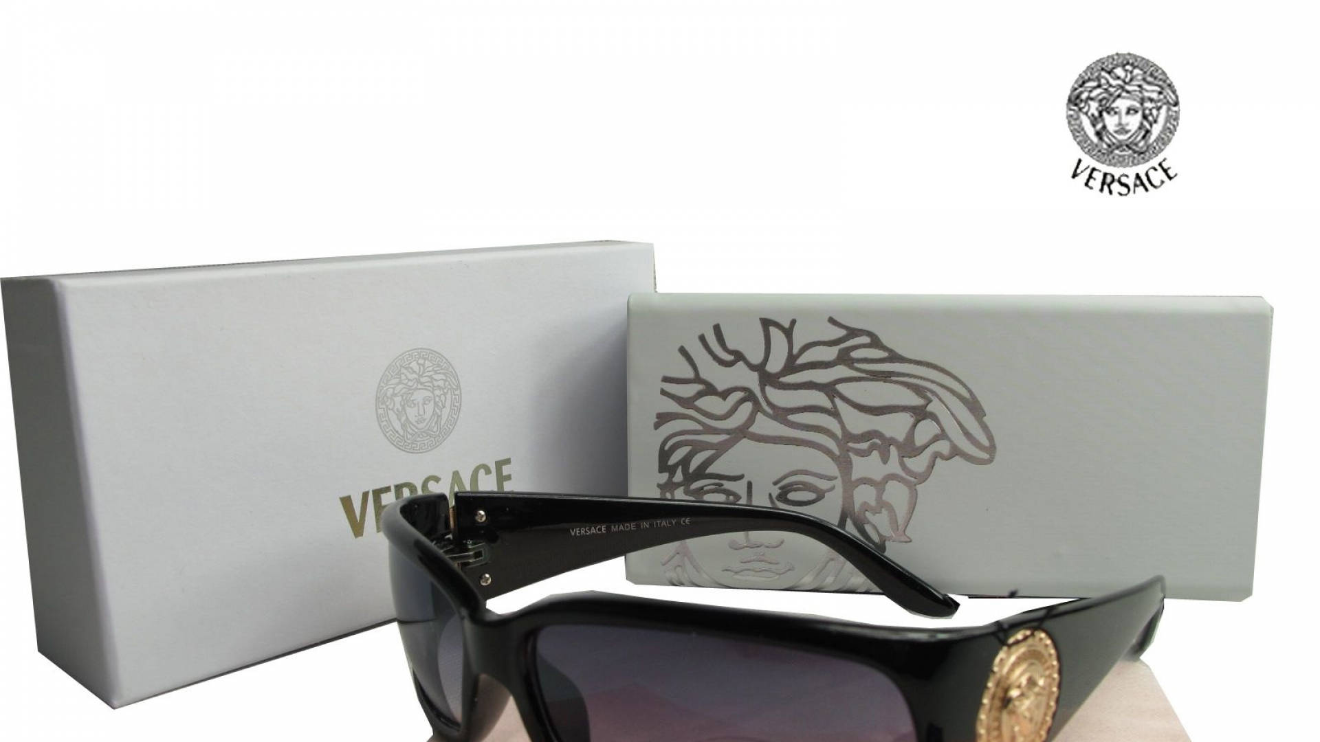 Sunglasses 桌布 壁紙 — 黑色 Versace 太陽眼鏡，帶金色美杜莎標誌，展示在品牌白色盒子旁，背景為純白色。