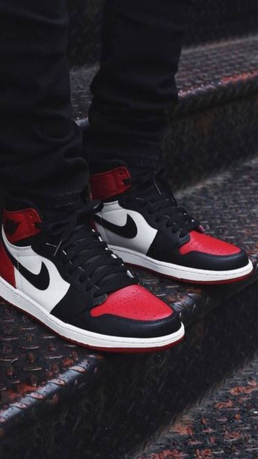 Nike Air Jordan 1 桌布 壁紙 — 黑色、紅色和白色Nike Air Jordan 1運動鞋在紋理混凝土階梯上的特寫。