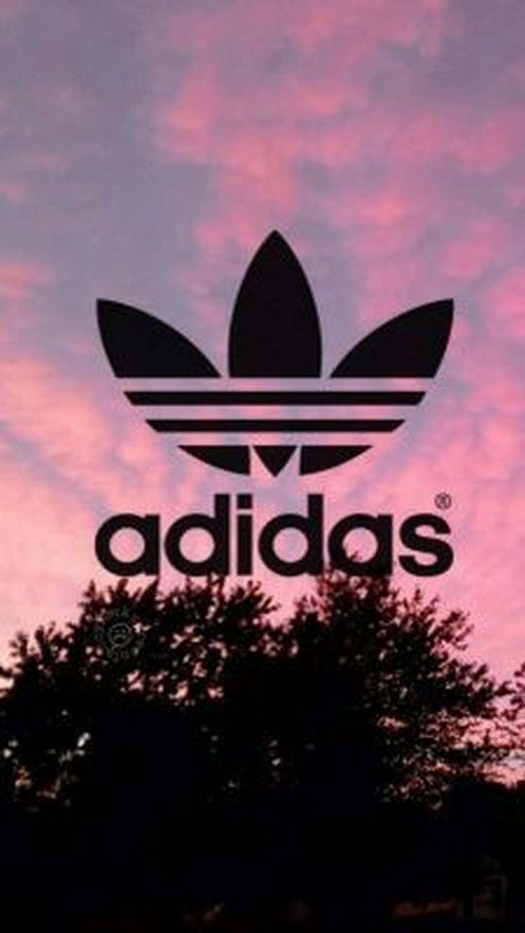 愛迪達 桌布 壁紙 — 黑色Adidas標誌剪影，襯著充滿活力的粉紅和紫色日落天空，下方有深色樹梢。