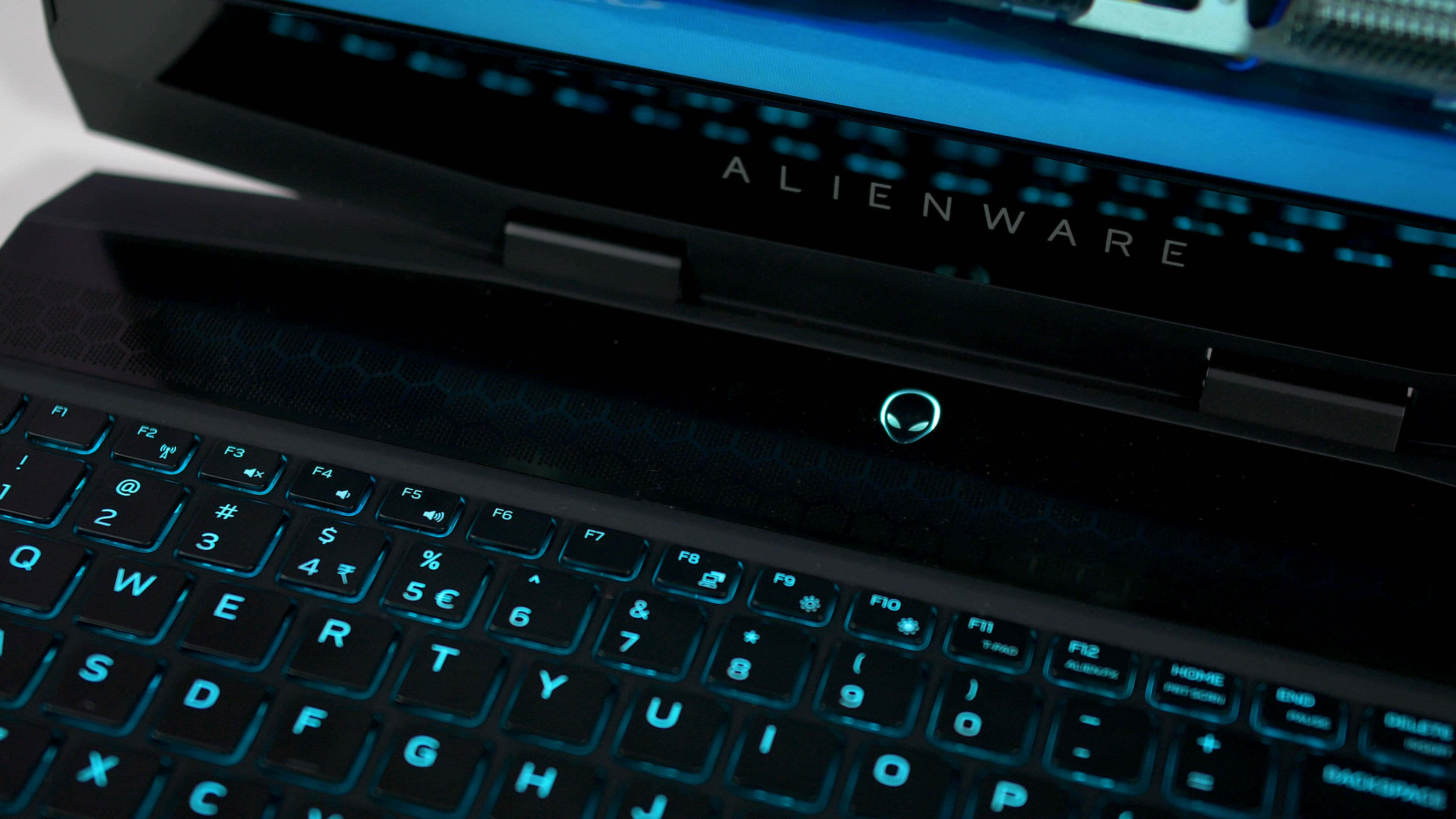 外星人 桌布 壁紙 — 黑色Alienware筆記型電腦特寫，帶有發光藍色鍵盤和標誌，背景為深色。