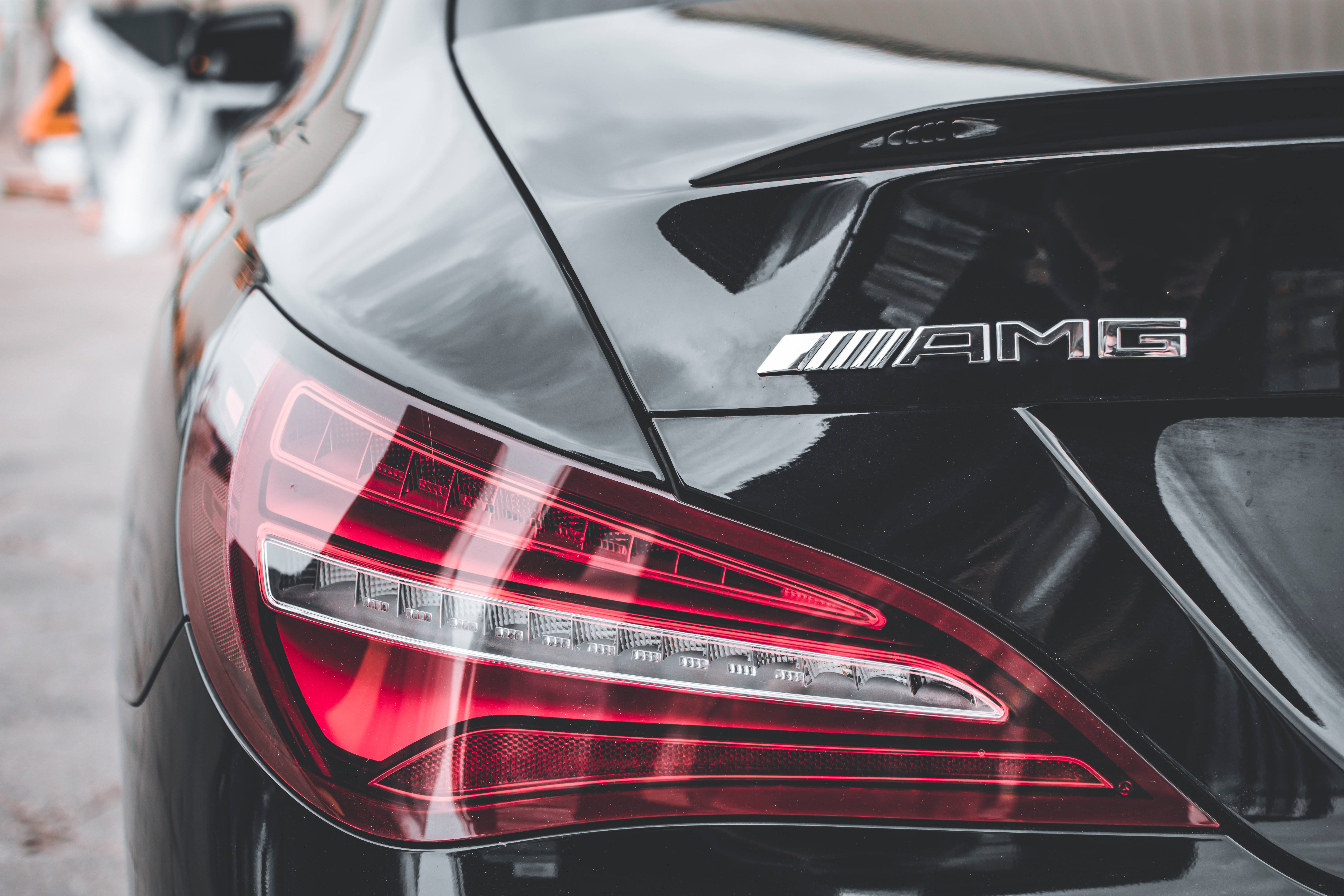 Mercedes Amg 桌布 壁紙 — 黑色AMG汽車後方特寫，配備發光紅色尾燈和鍍鉻標誌。