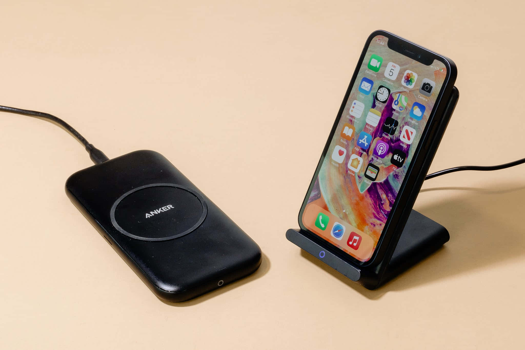 Wireless Charging 桌布 壁紙 — 黑色Anker無線充電器和iPhone放在支架上，置於米色表面，帶有柔和陰影。