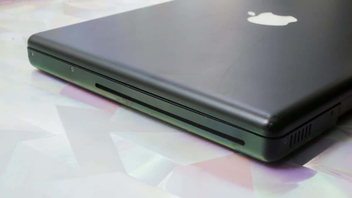 Black Macbook 桌布 壁紙 — 黑色Apple筆記型電腦特寫，放置在色彩繽紛的幾何圖案表面上。