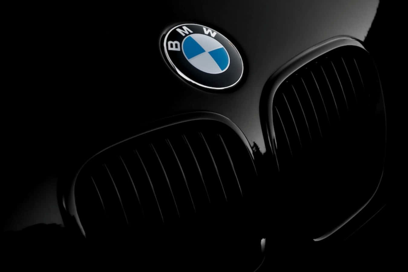 Bmw Logo 桌布 壁紙 — 黑色BMW汽車標誌性腎形水箱護罩和標誌在黑暗背景下亮起的特寫。