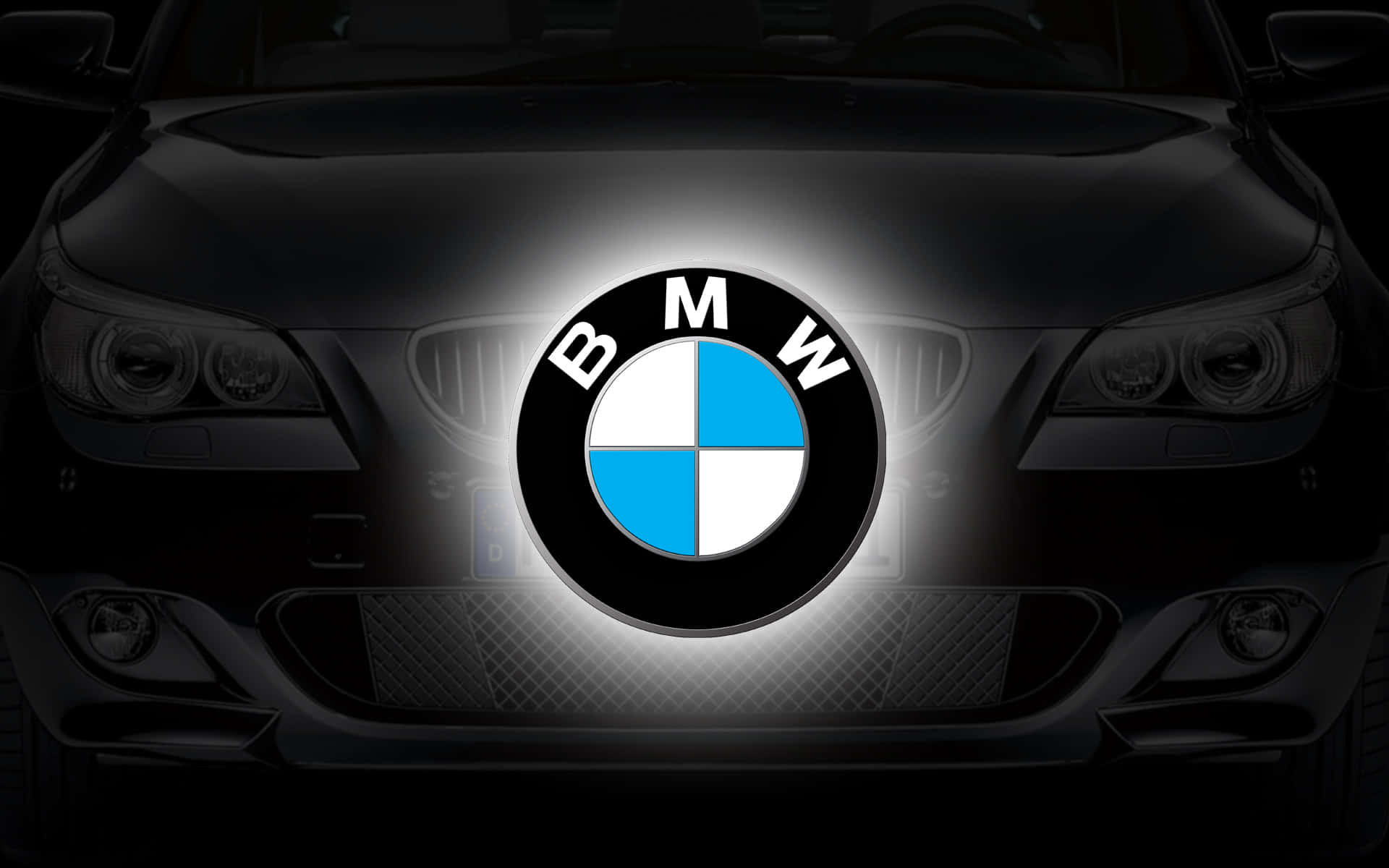 BMW 動圖 桌布 壁紙 — 黑色BMW汽車的前格柵在夜間發出藍白色BMW標誌的光芒。