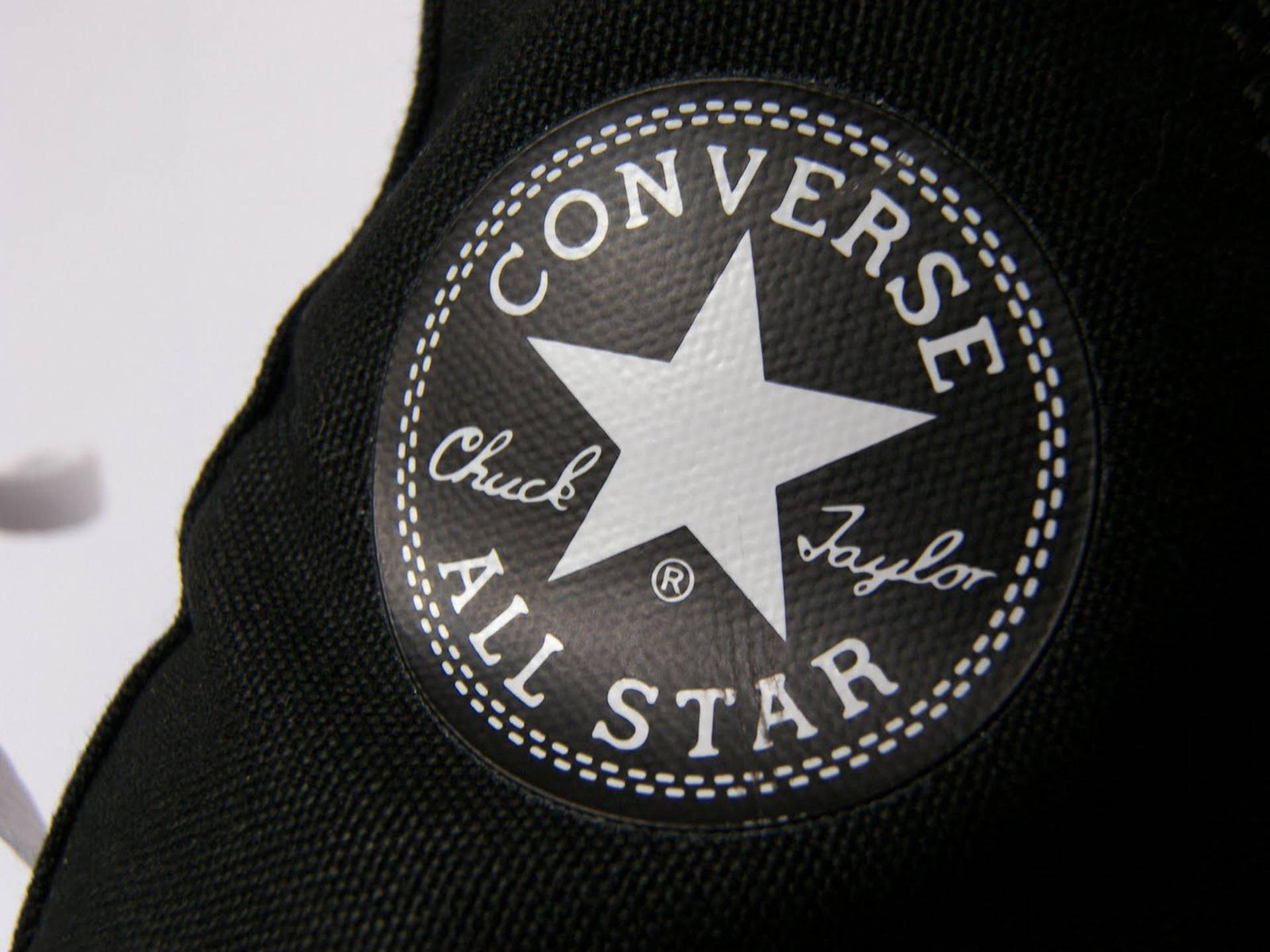 Converse Logo 桌布 壁紙 — 黑色Converse Chuck Taylor All Star標誌布章特寫，帶有白色縫線和星星，位於帆布上。