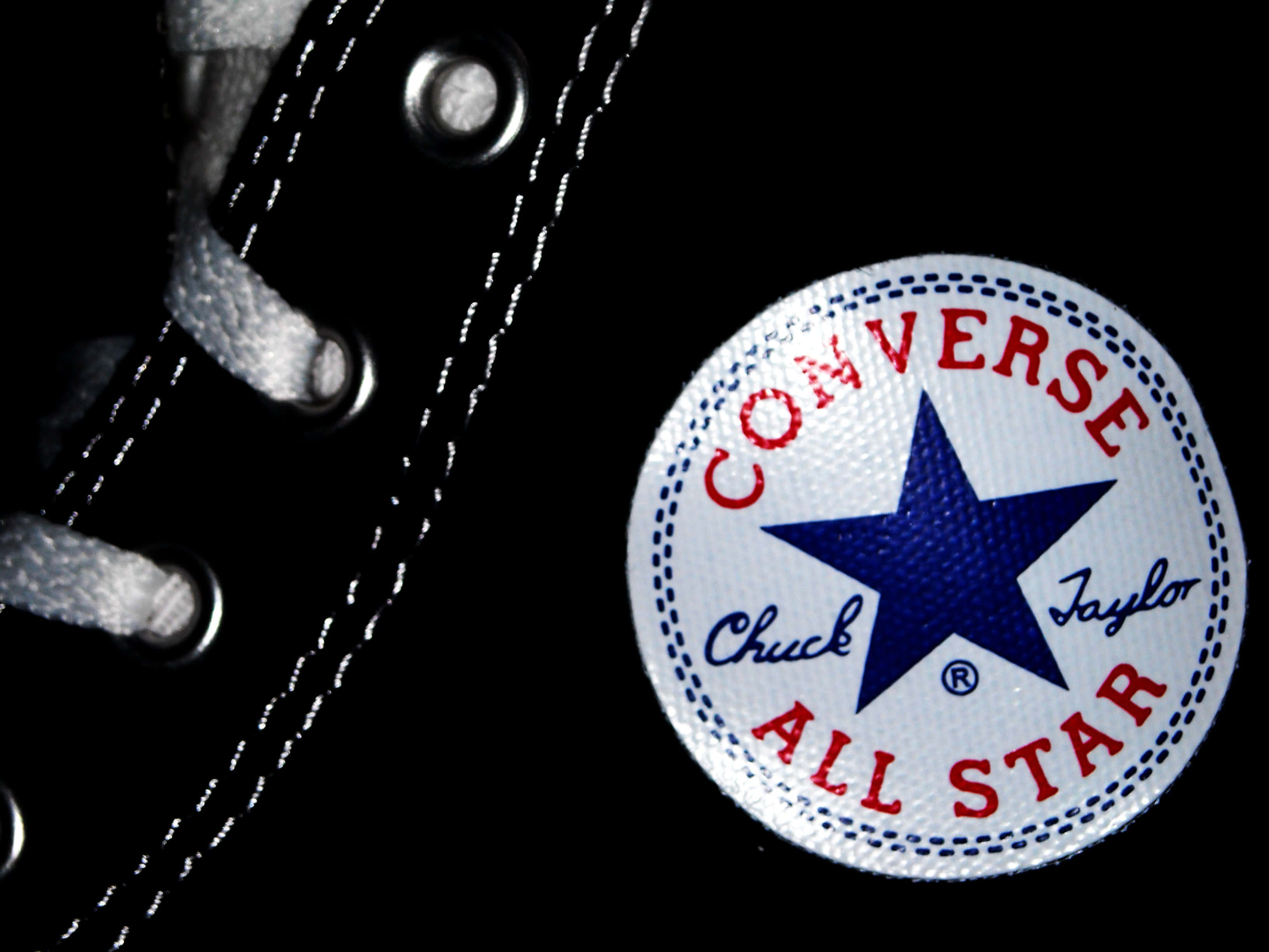 Converse 標誌 桌布 壁紙 — 黑色Converse Chuck Taylor All Star運動鞋特寫，白色鞋帶和縫線，背景深色。
