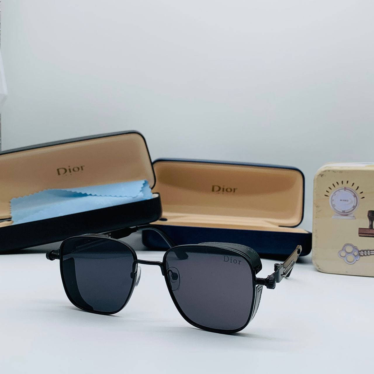 黑色Dior太陽眼鏡、品牌眼鏡盒及復古收音機在白色背景上。 — Dior 動態 壁紙
