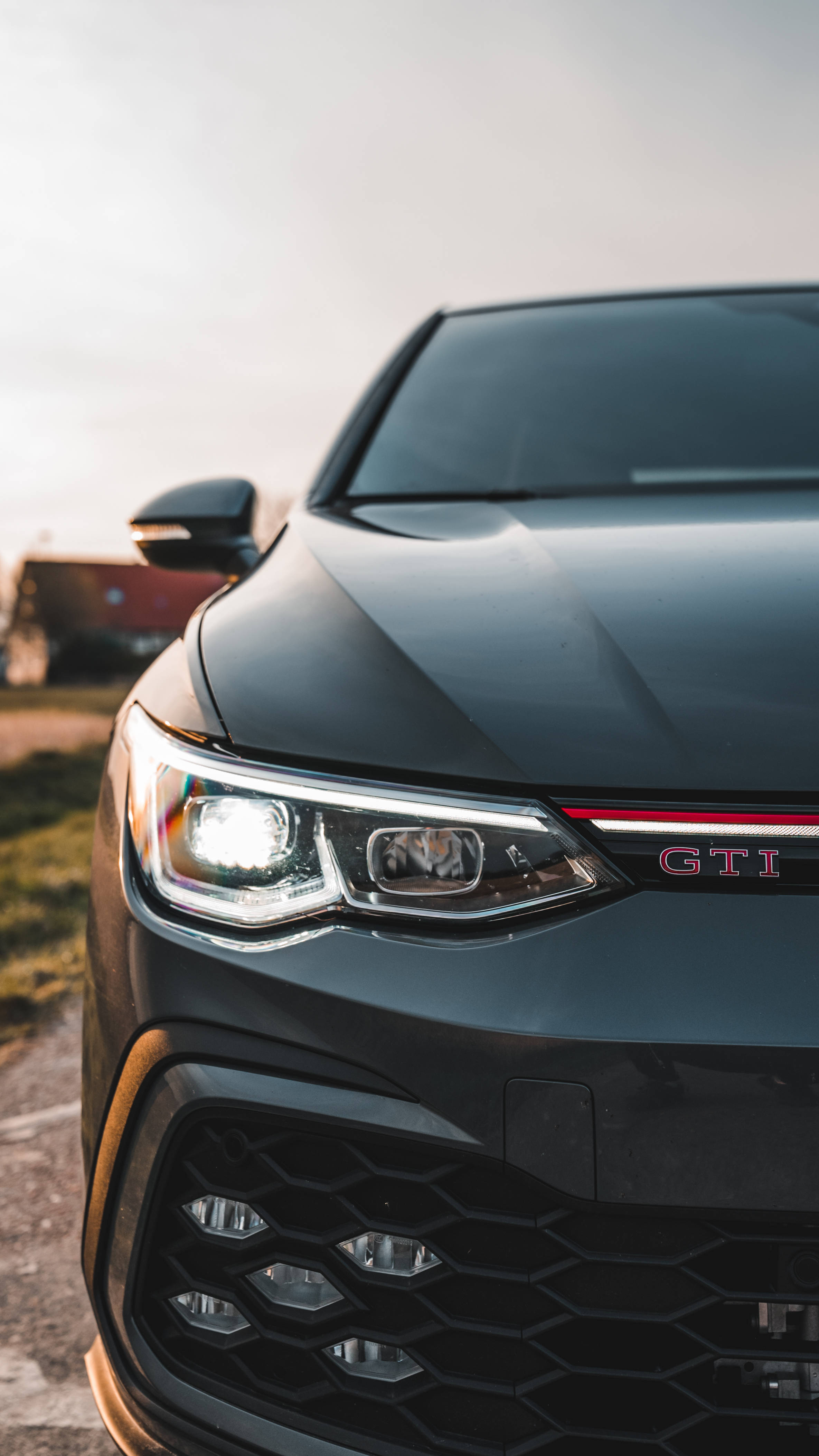 Gti 桌布 壁紙 — 黑色GTI汽車的車頭格柵和頭燈在柔和的金色日落光線下閃耀的特寫。