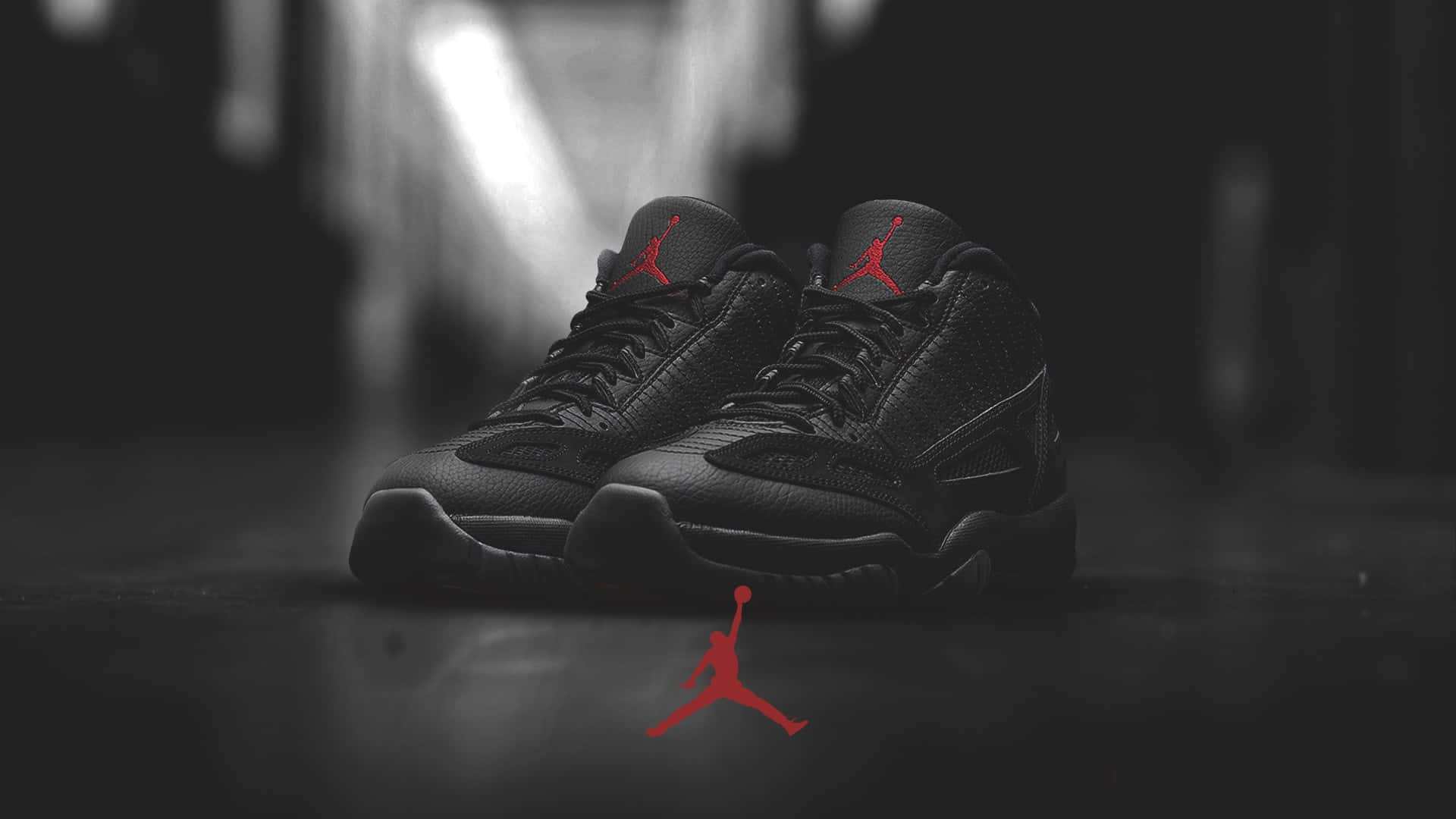 鞋子 桌布 壁紙 — 黑色Jordan 11運動鞋帶有紅色Jumpman標誌，在黑暗地板上置於戲劇性的聚光燈下。