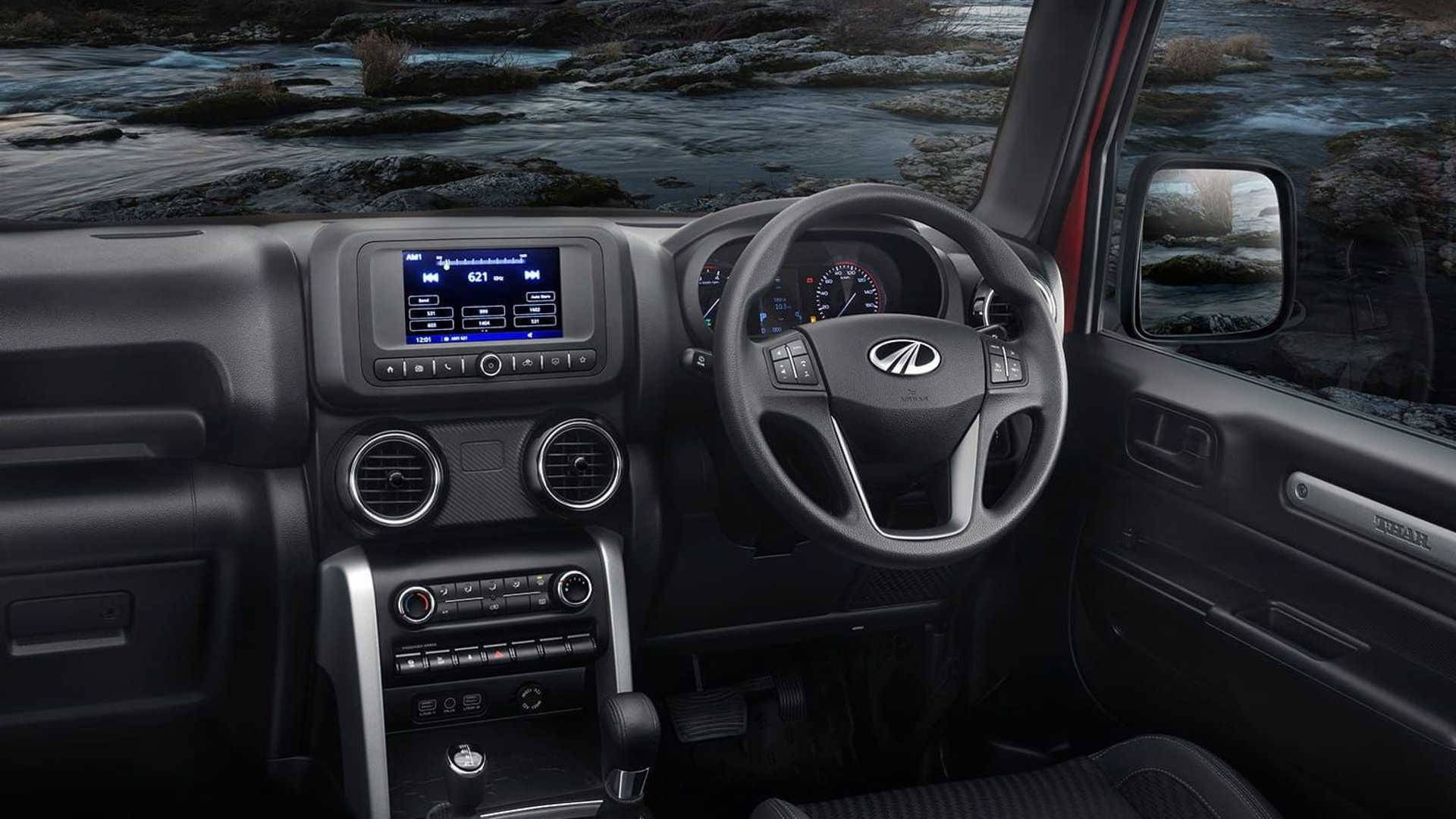 高清 桌布 壁紙 — 黑色Mahindra Thar SUV的內部，顯示儀表板控制裝置和方向盤，從駕駛座望向雪覆蓋的河流景觀。
