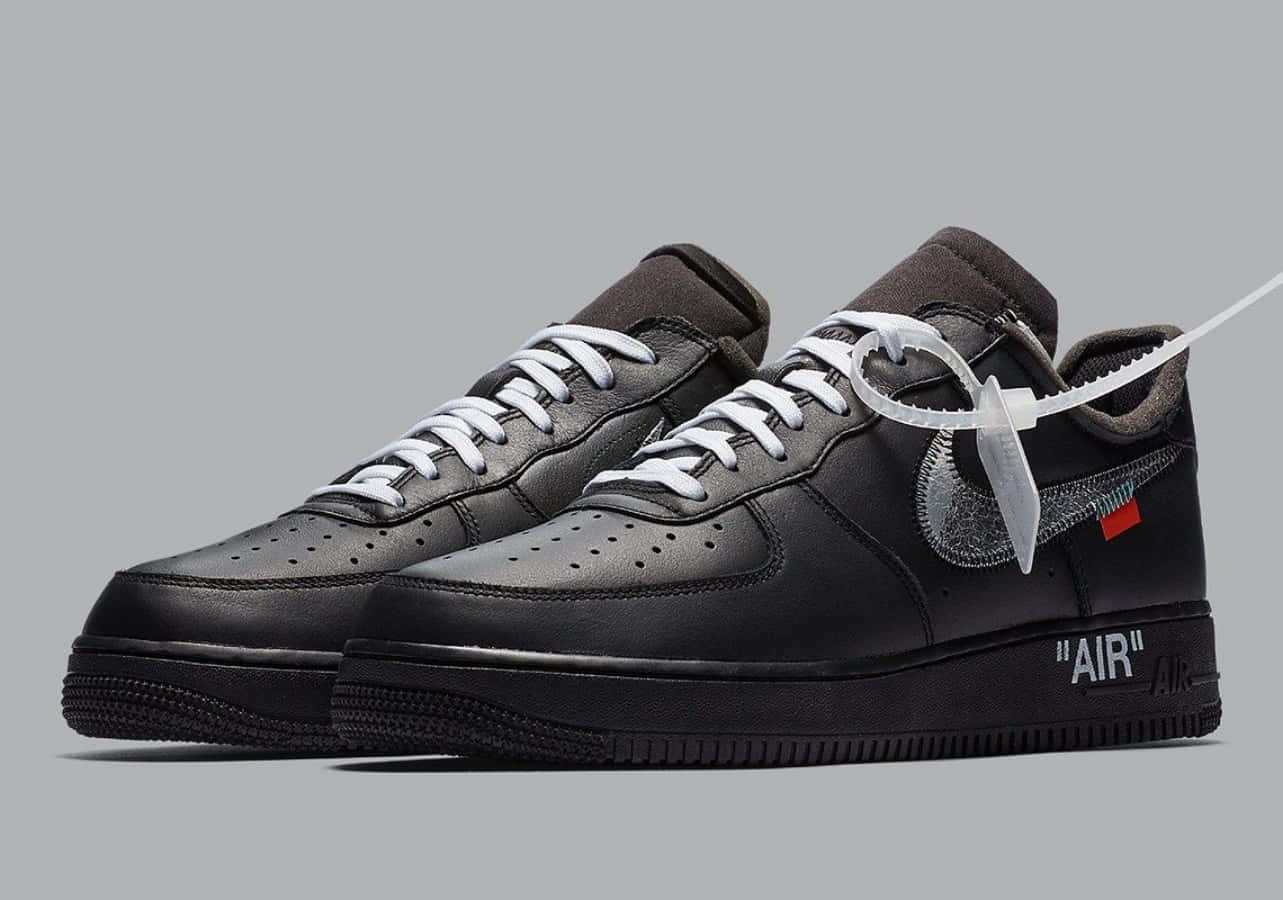 桌布 壁紙 — 黑色Nike Air Force 1運動鞋，配有白色鞋帶和鞋跟處獨特的白色標籤，背景為灰色。