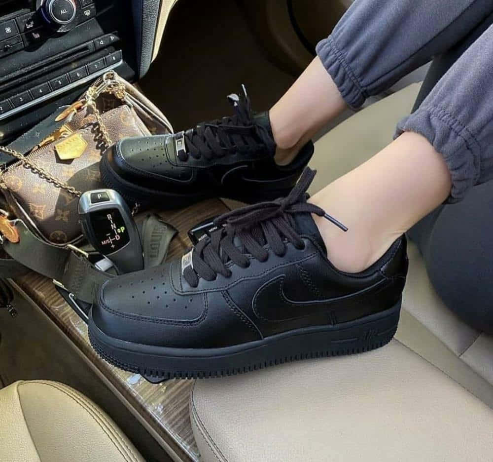 Black Air Force 桌布 壁紙 — 黑色Nike Air Force 1運動鞋穿在車內人士腳上的特寫，車內有豪華配件。