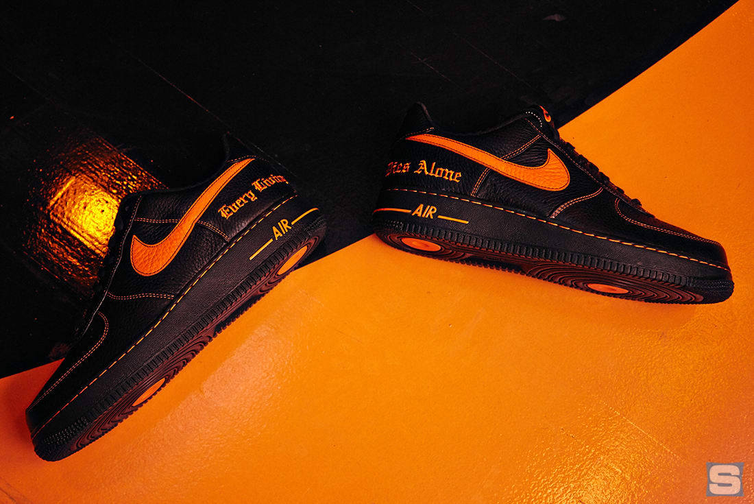 Vlone 桌布 壁紙 — 黑色Nike Air Force 1運動鞋帶有鮮明的橙色點綴，斜放在充滿活力的橙色表面上，背景為深色紋理。