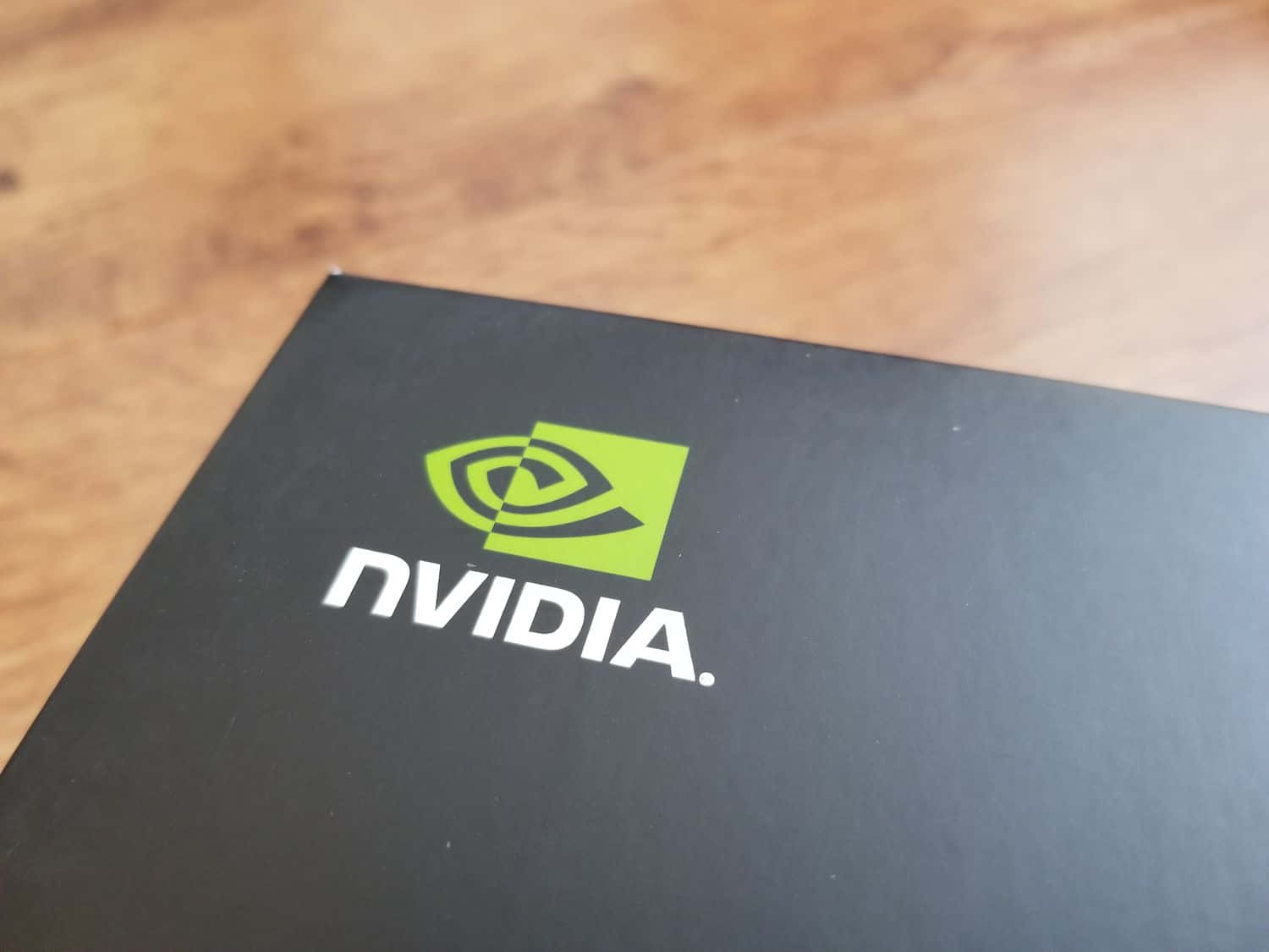 nvidia 桌布 壁紙 — 黑色NVIDIA盒子特寫，帶有綠色標誌，放在木質表面上。