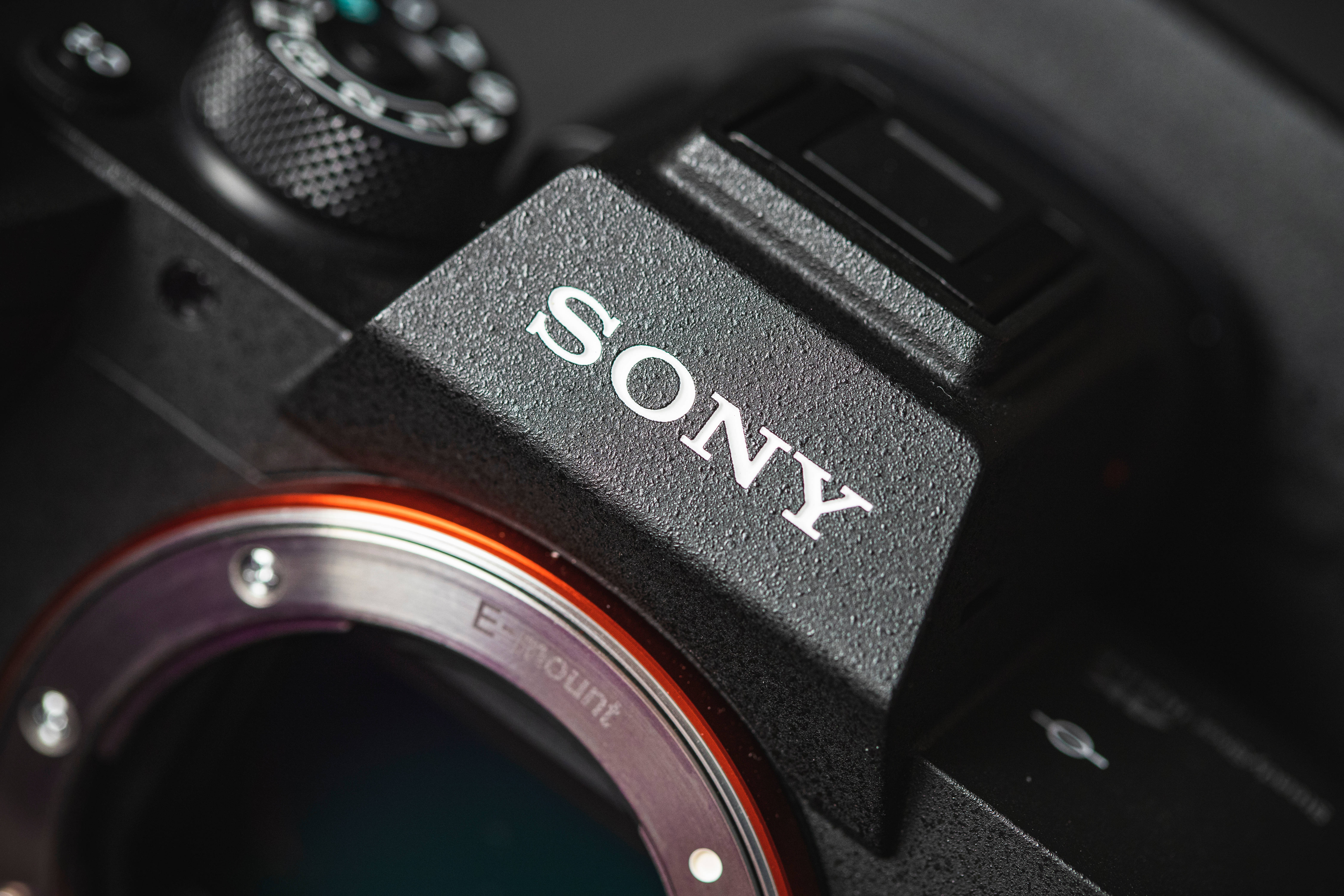 Sony 桌布 壁紙 — 黑色Sony相機機身特寫，顯示品牌標誌和帶有橙色裝飾環的鏡頭接環。
