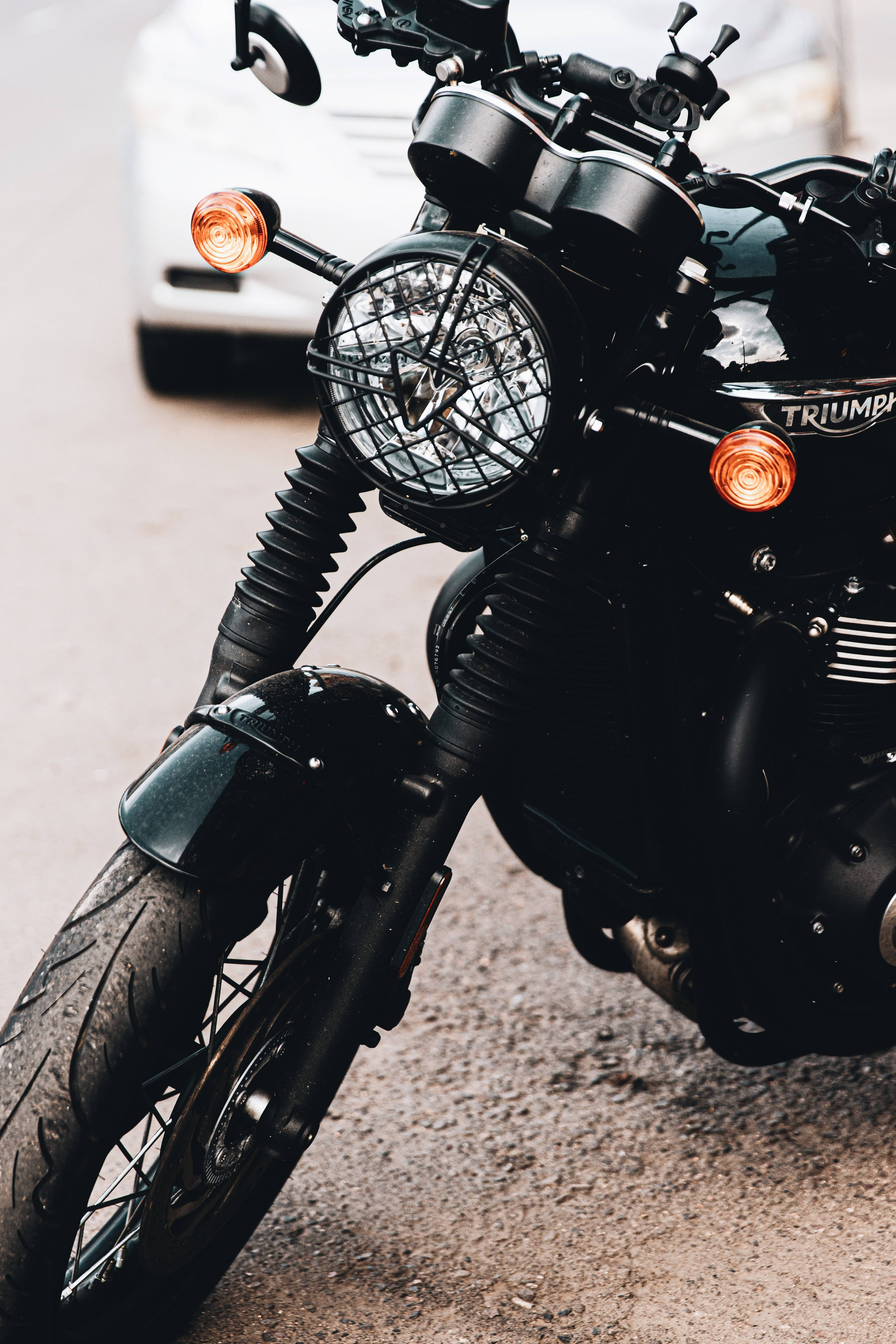 機車 桌布 壁紙 — 黑色Triumph機車近距離特寫，帶橙色方向燈，停在碎石路上。